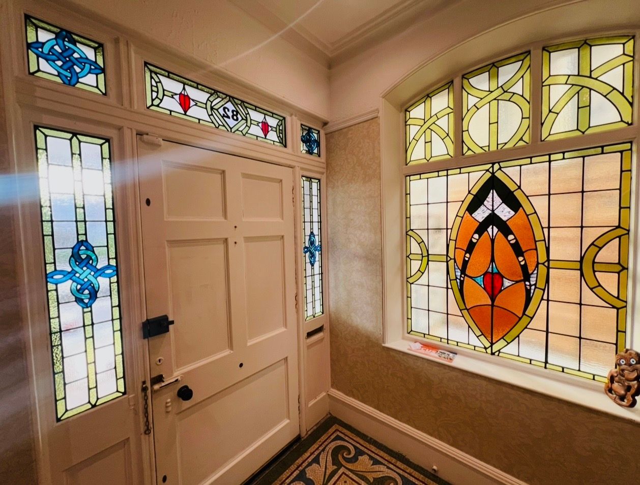 Front entry with white door and colorful stained-glass side and transom windows