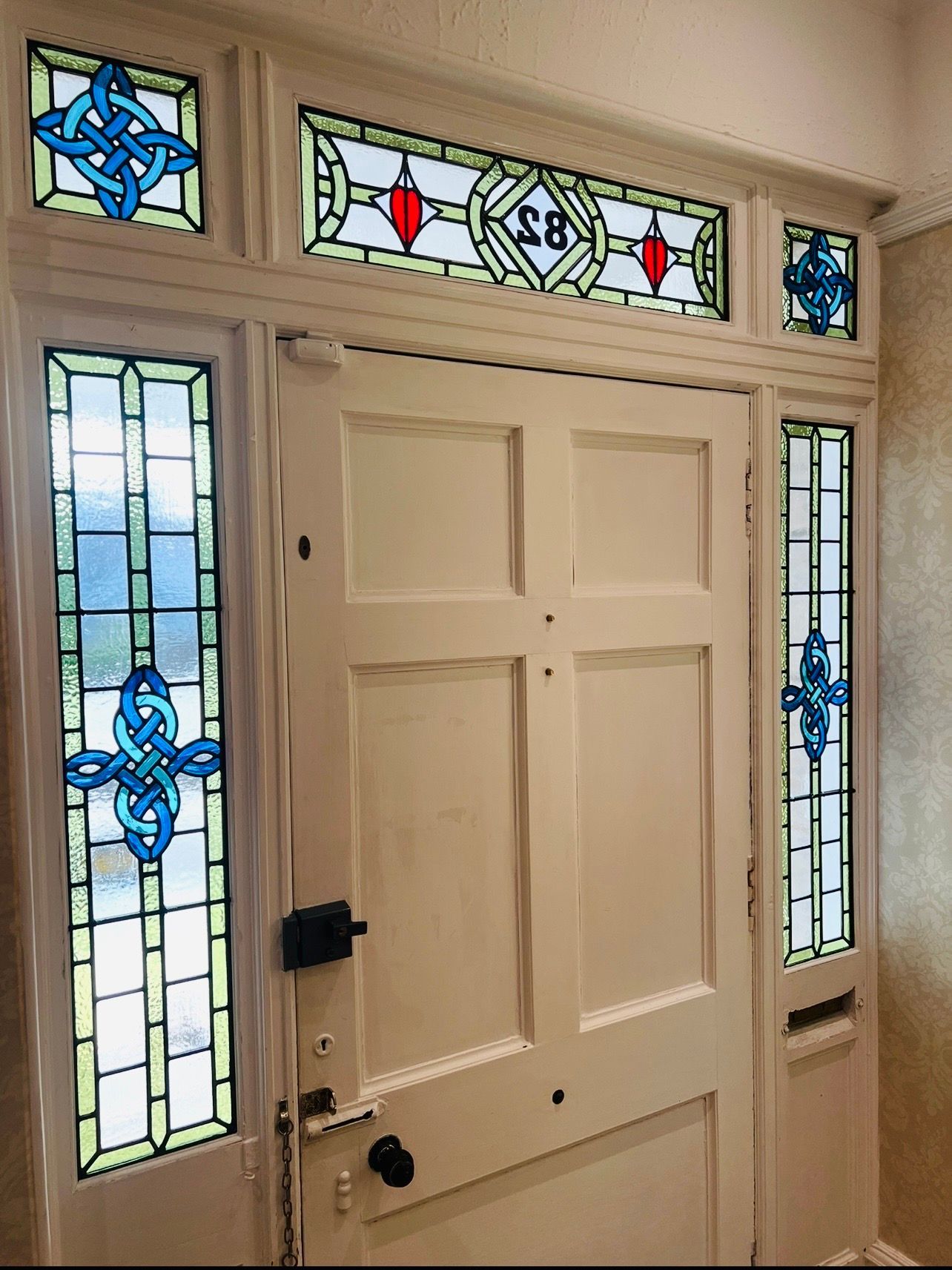 White front door with blue-and-clear stained glass sidelights and transom windows
