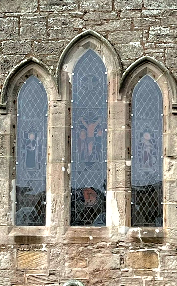 Three narrow arched stained-glass windows set in a stone church wall