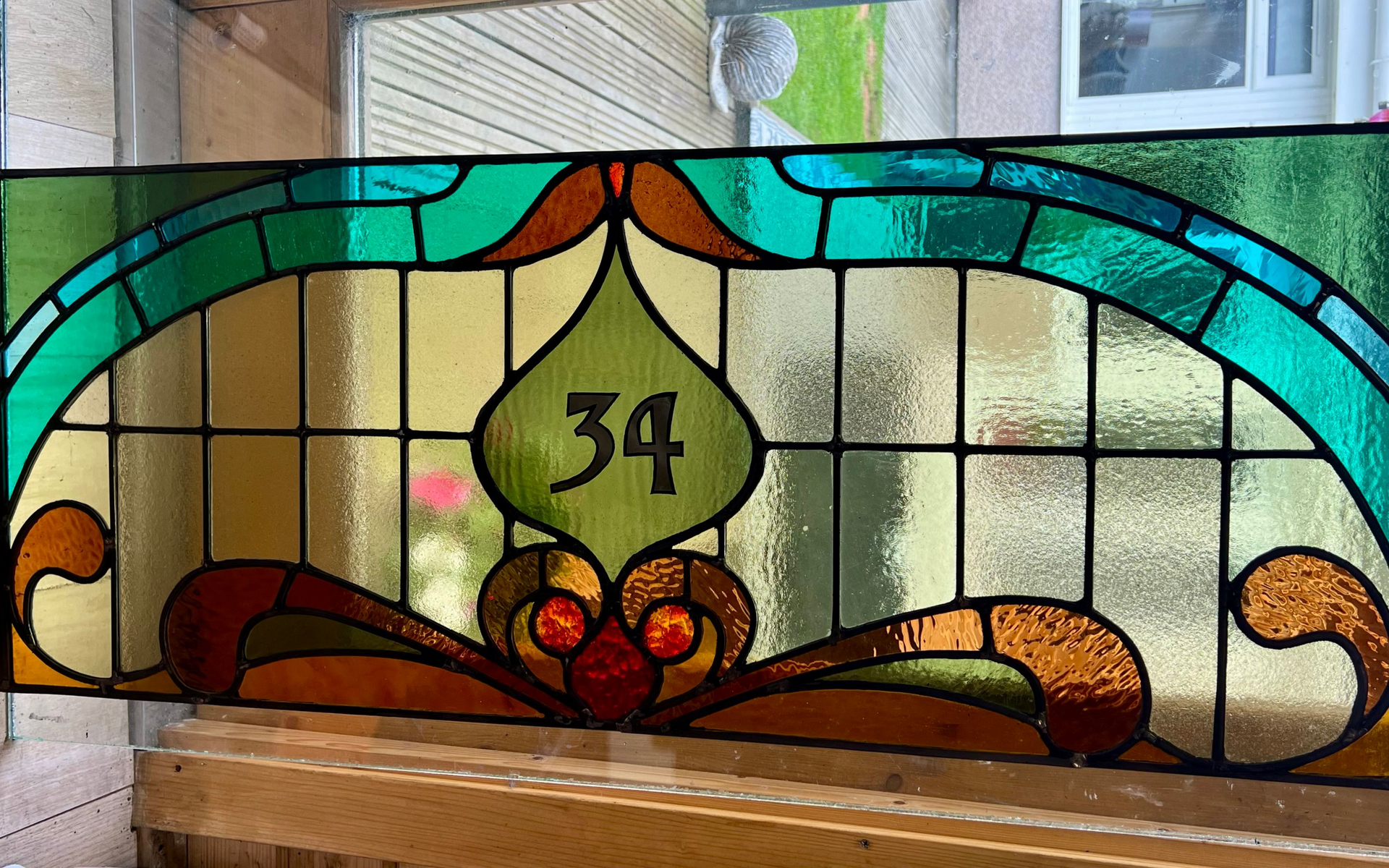 Stained-glass window with the number 34, featuring teal, amber, and green floral motifs.