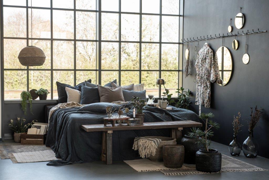 Ein Schlafzimmer mit einem großen Bett und einer Bank vor einem großen Fenster.