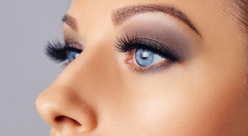 A close up of a woman 's face with blue eyes and long eyelashes.