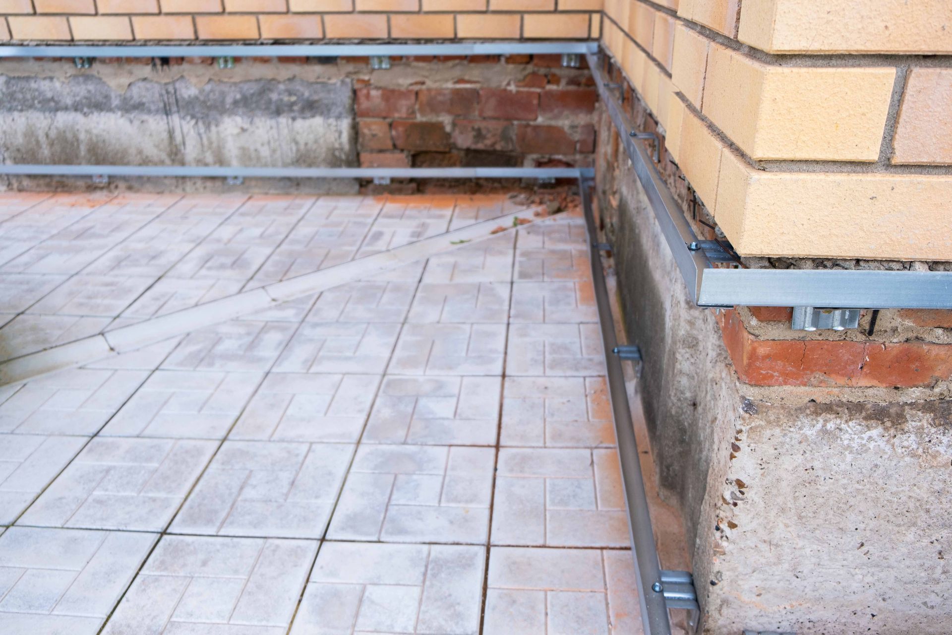 Brick wall corner with light-colored tile flooring and metal edging. Brick wall corner with light-colored tile flooring and metal edging.