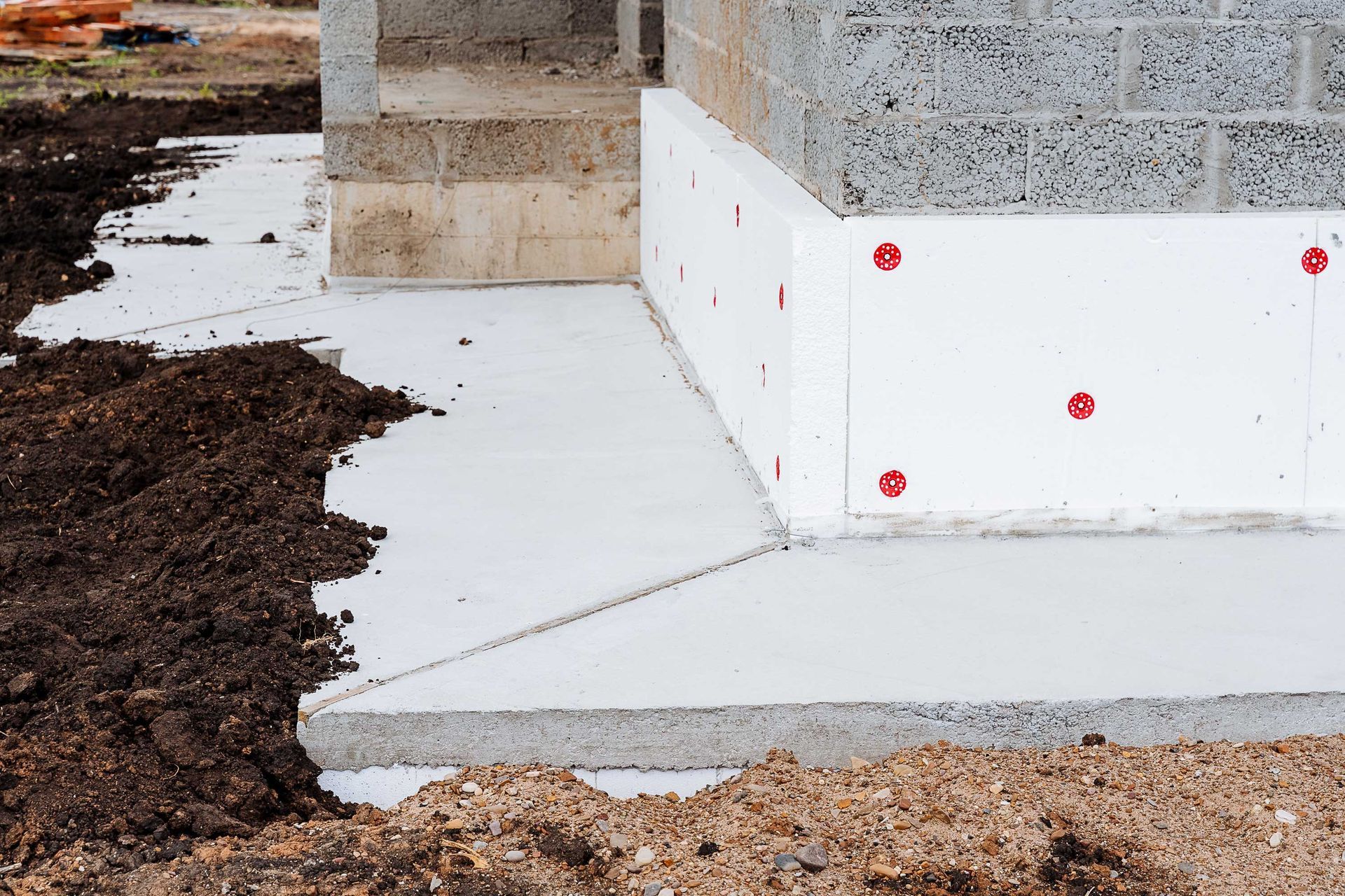 Foundation of a building under construction, with concrete and white insulation against cinder blocks and dirt. Foundation of a building under construction, with concrete and white insulation against cinder blocks and dirt.