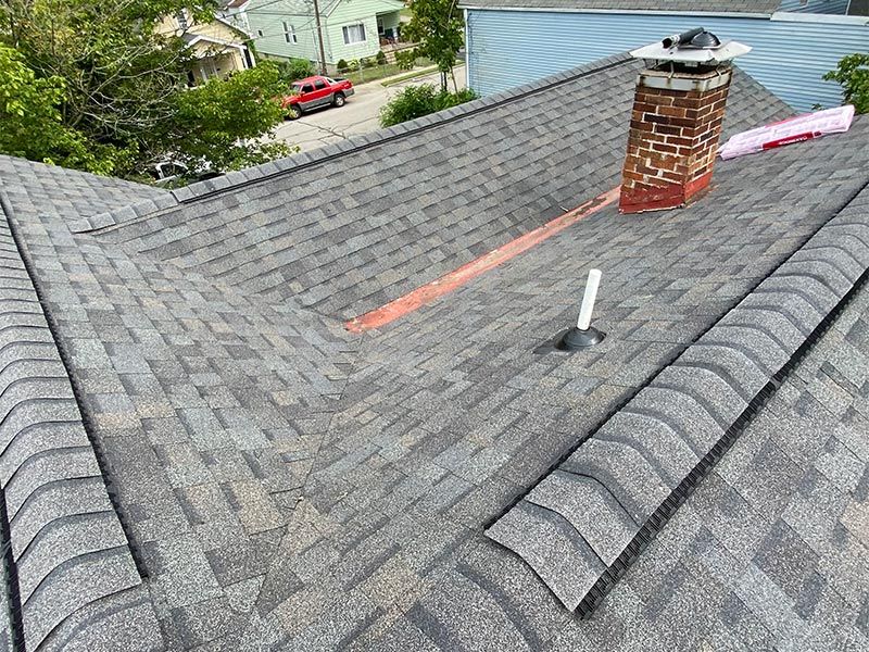 Gray shingled roof with a brick chimney, vent pipe, and a red marking line near the ridge.