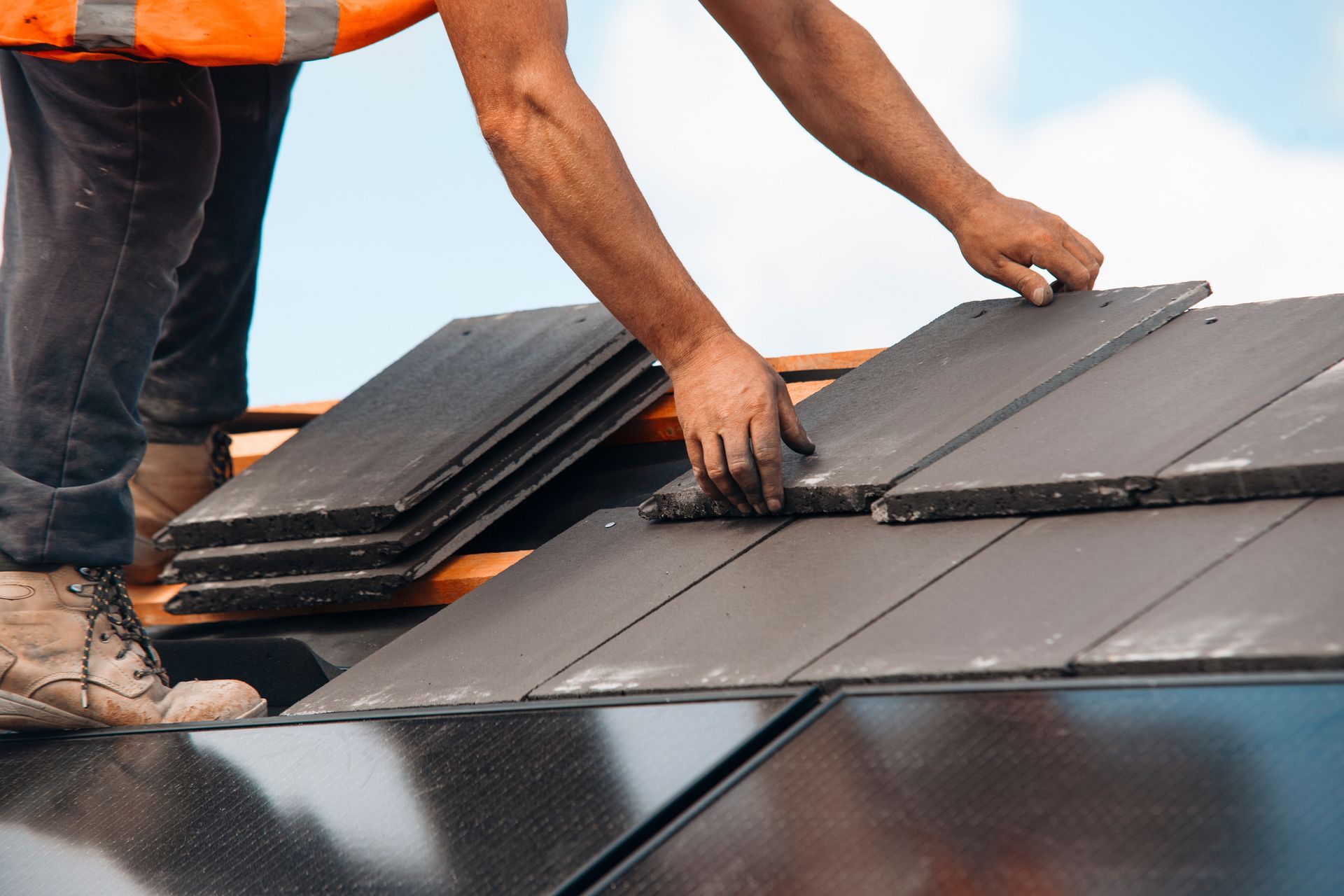 Siding Installation and Repairs Near You Workers installing slate roof shingles on a house