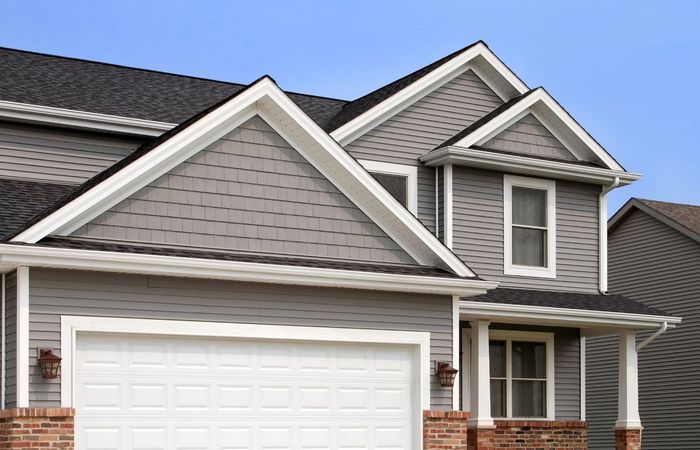 A house with a white garage door and a black roof. A house with a white garage door and a black roof.