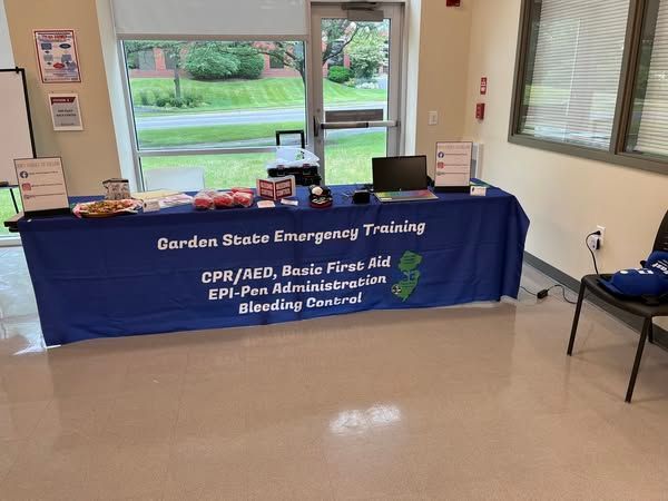 A blue informational table for Garden State Emergency Training, offering CPR, first aid, and EpiPen courses.