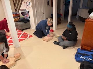 People practicing CPR on medical mannequins during a training session in a carpeted room.