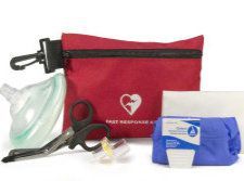 A red first aid kit bag accompanied by a CPR mask, medical shears, and a small blue first aid supply pack.