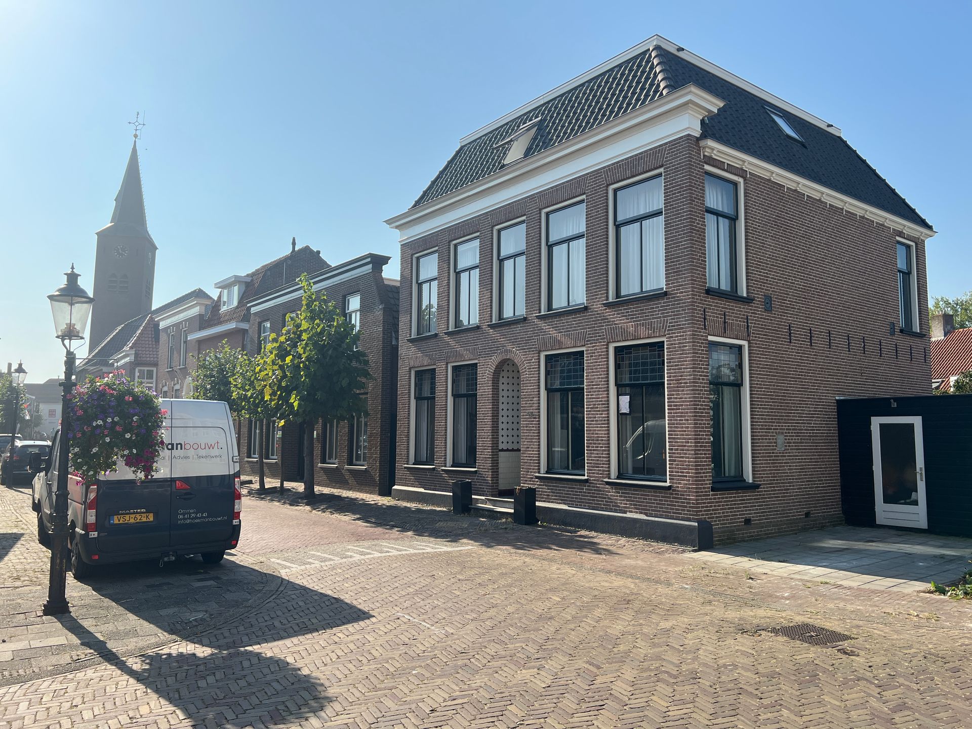 Een bakstenen gebouw met een wit busje ervoor geparkeerd.