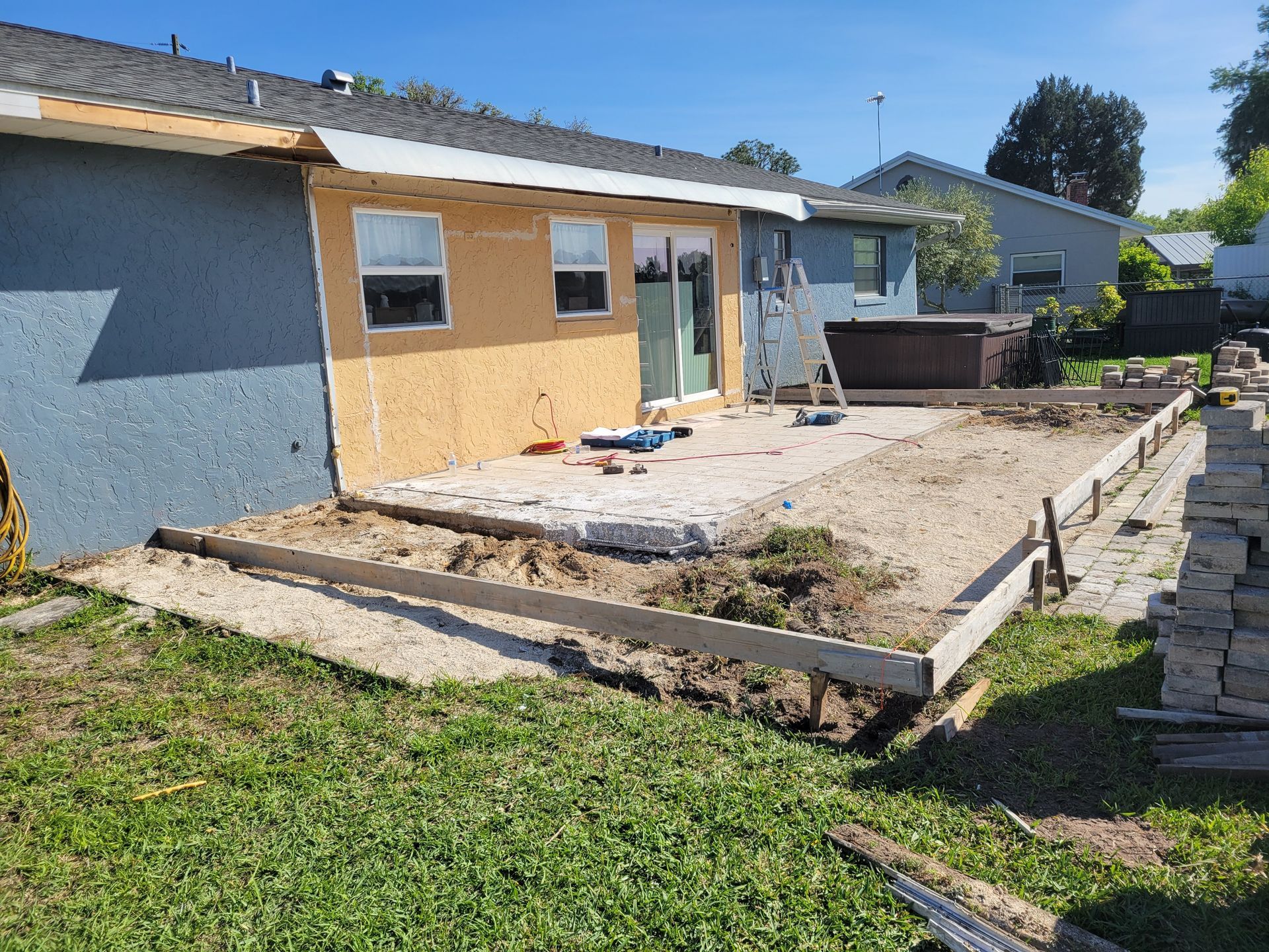 Partly renovated house exterior with a bare concrete patio and wooden forms under construction