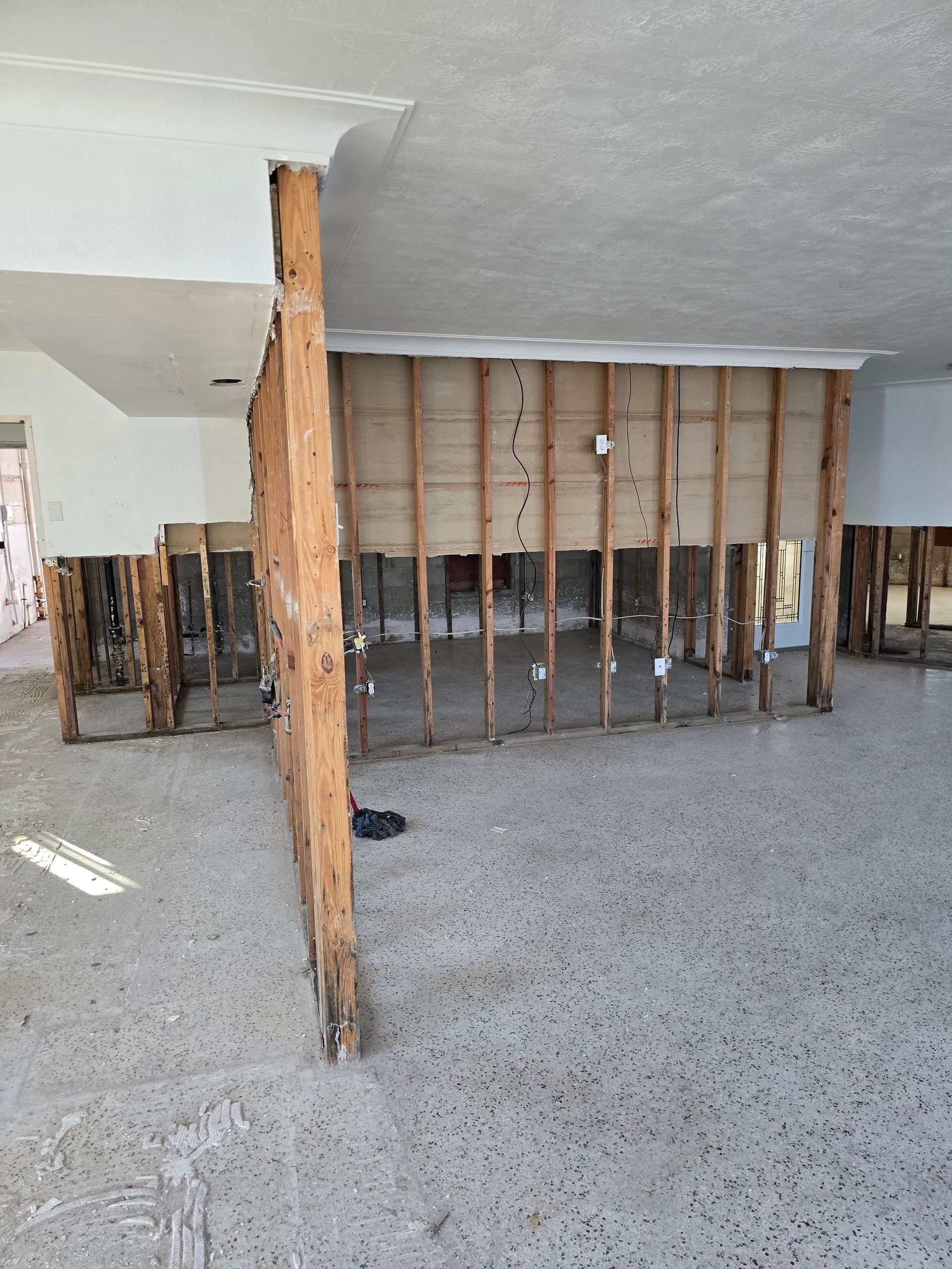 Flood-damaged room with exposed studs, wooden support posts, and debris-strewn floor