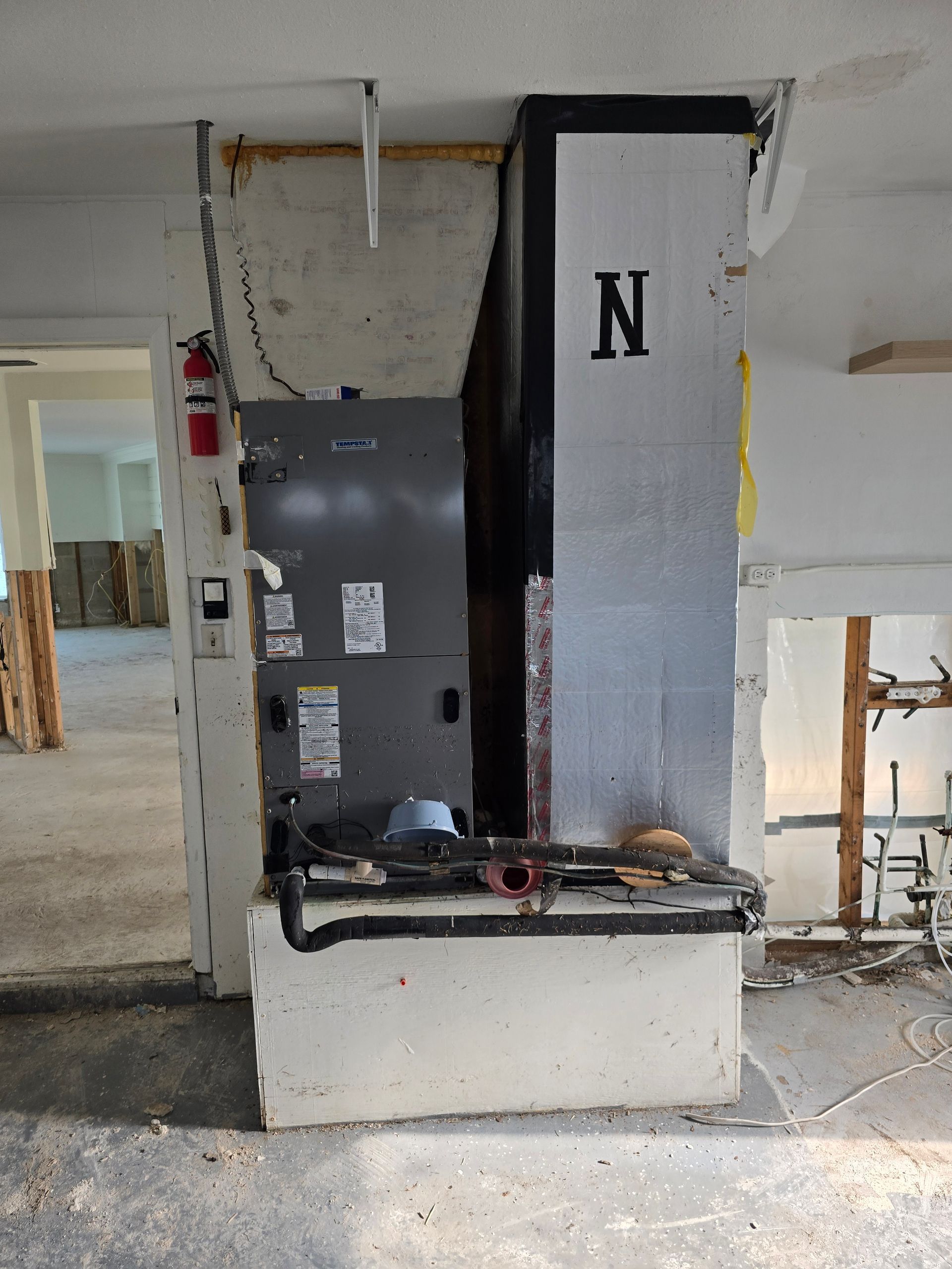 Vertical metal lift/elevator unit in a damaged room with exposed walls and debris on the floor