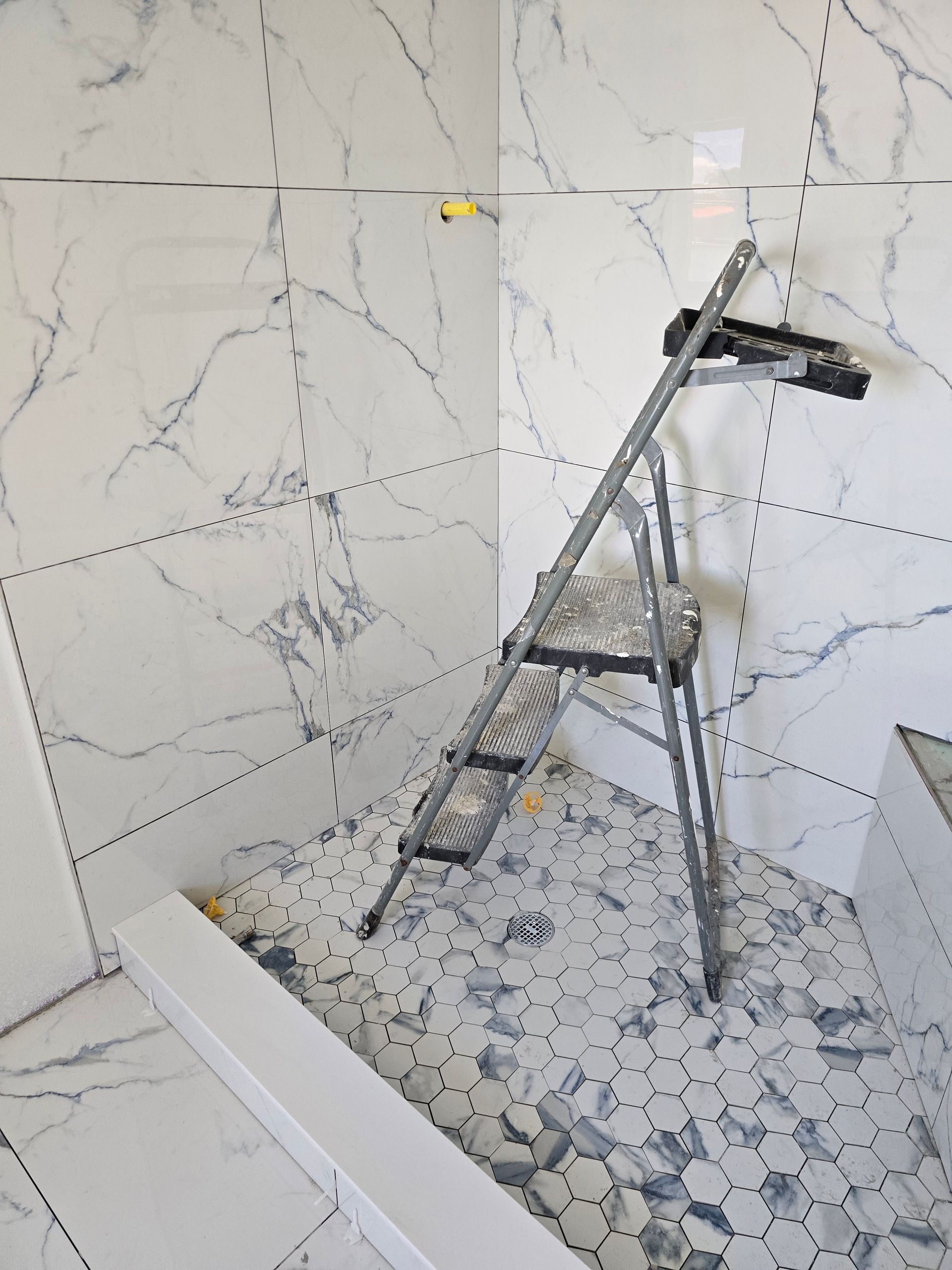 Renovation shower with tile walls, shower base, ladder, and tripod standing in the stall