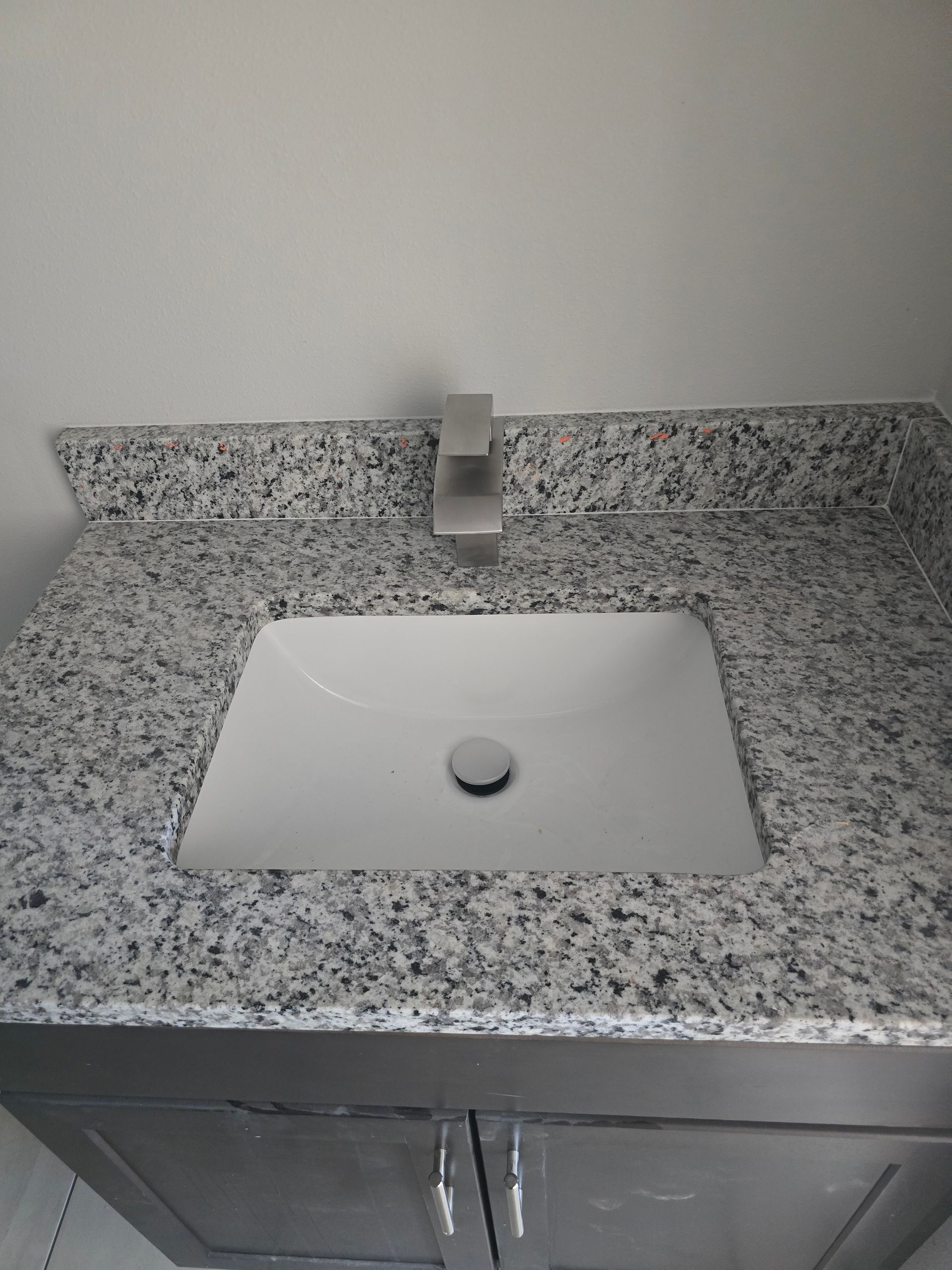 Granite bathroom sink with modern faucet and white basin on speckled countertop