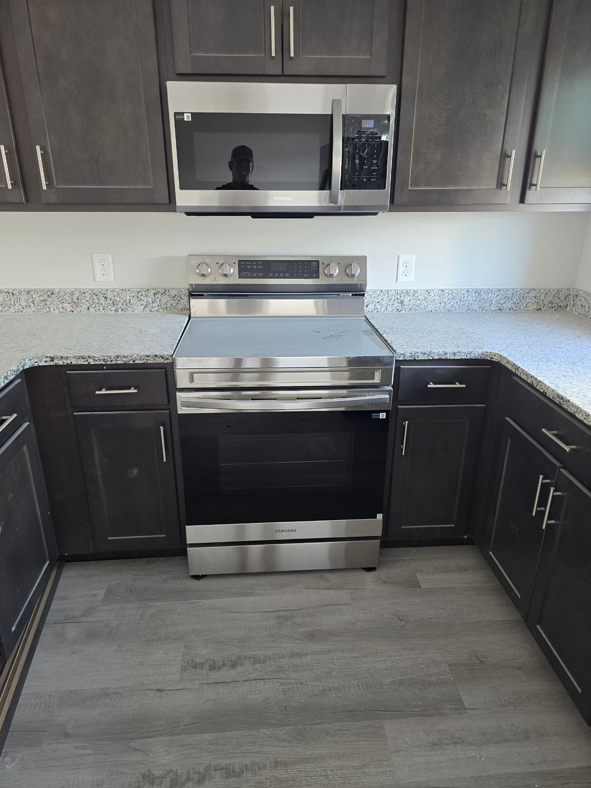 Modern kitchen with dark cabinets, stainless steel stove, and speckled countertop.