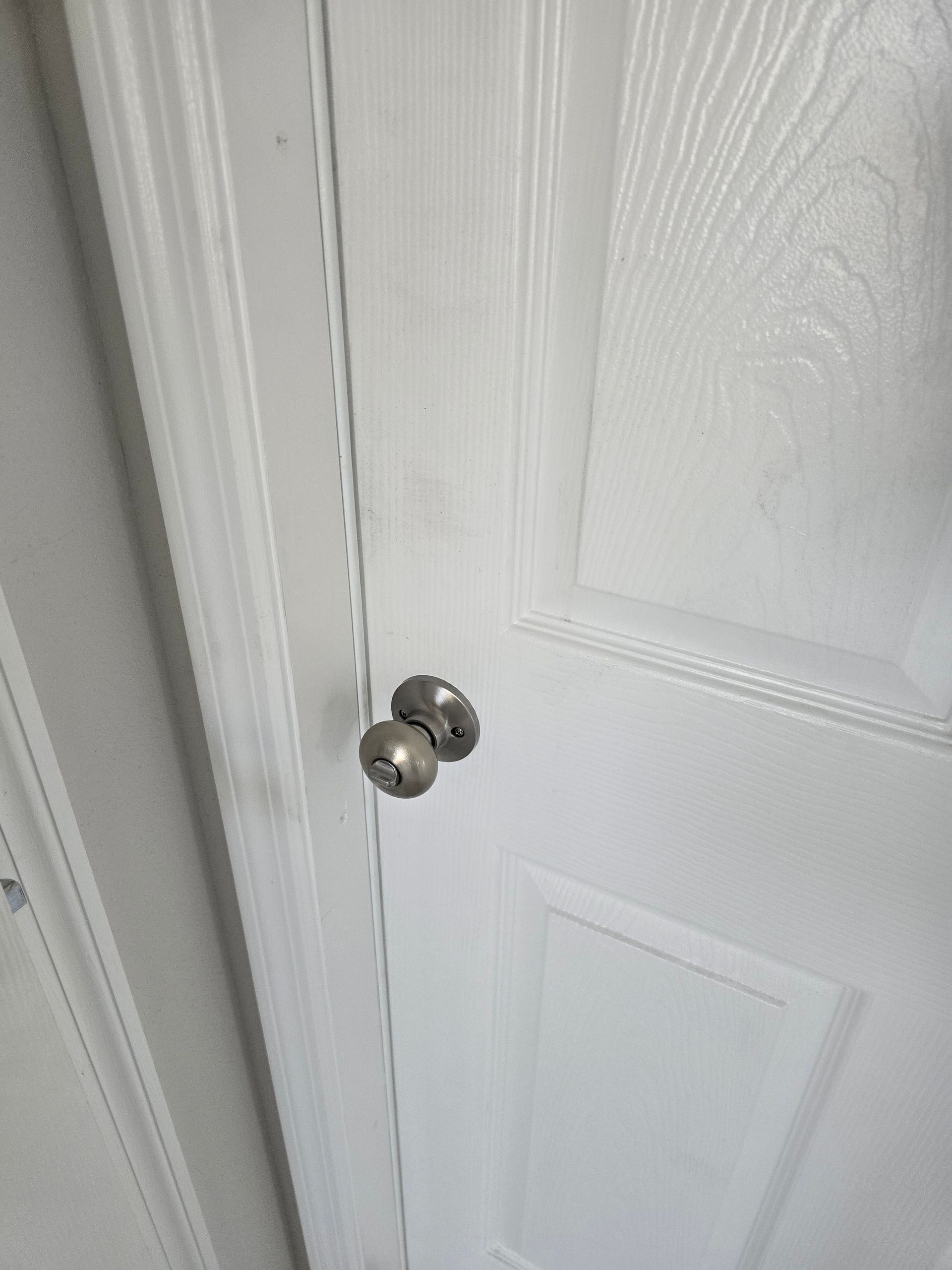 White interior door with a silver knob, viewed close up.