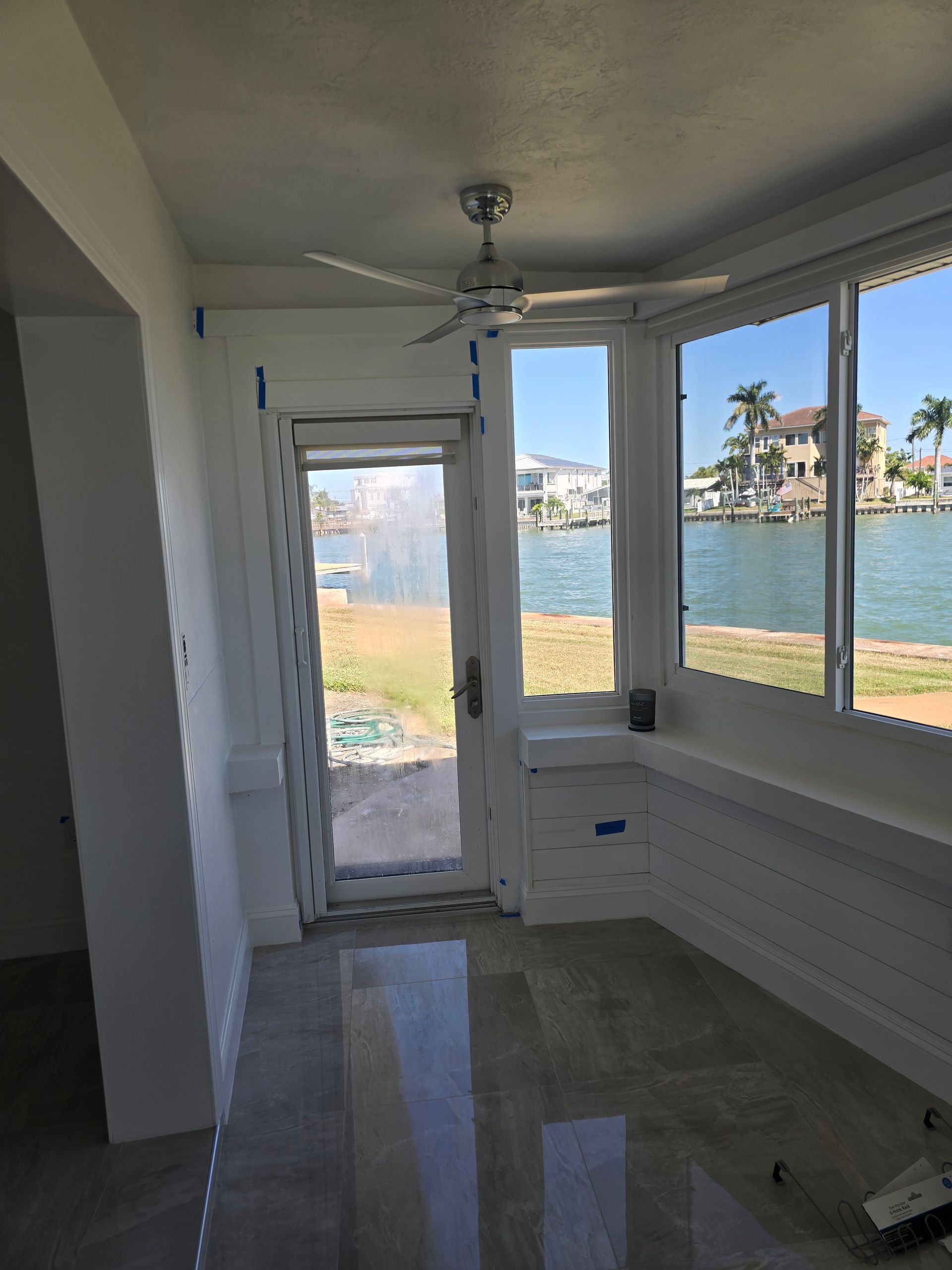 Empty room with bay windows and a glass door overlooking the water and waterfront homes