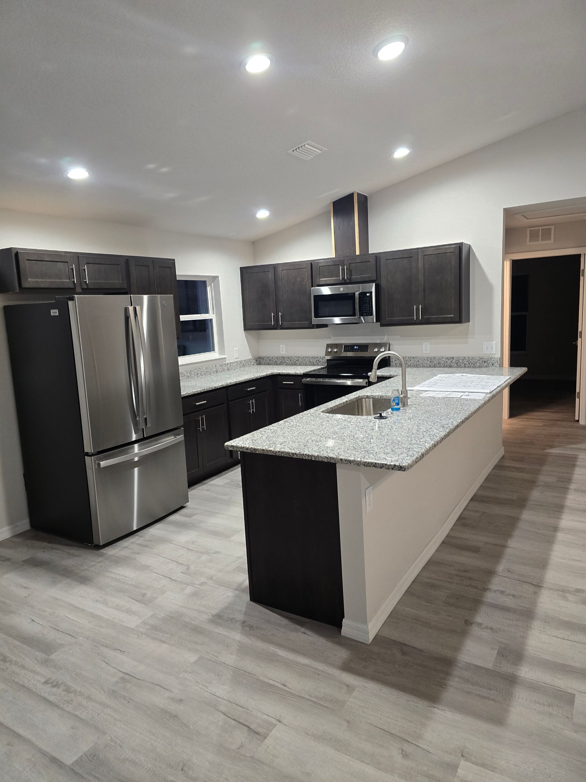 Bright white modern kitchen with marble island, gold pendant lights, and stainless steel appliances