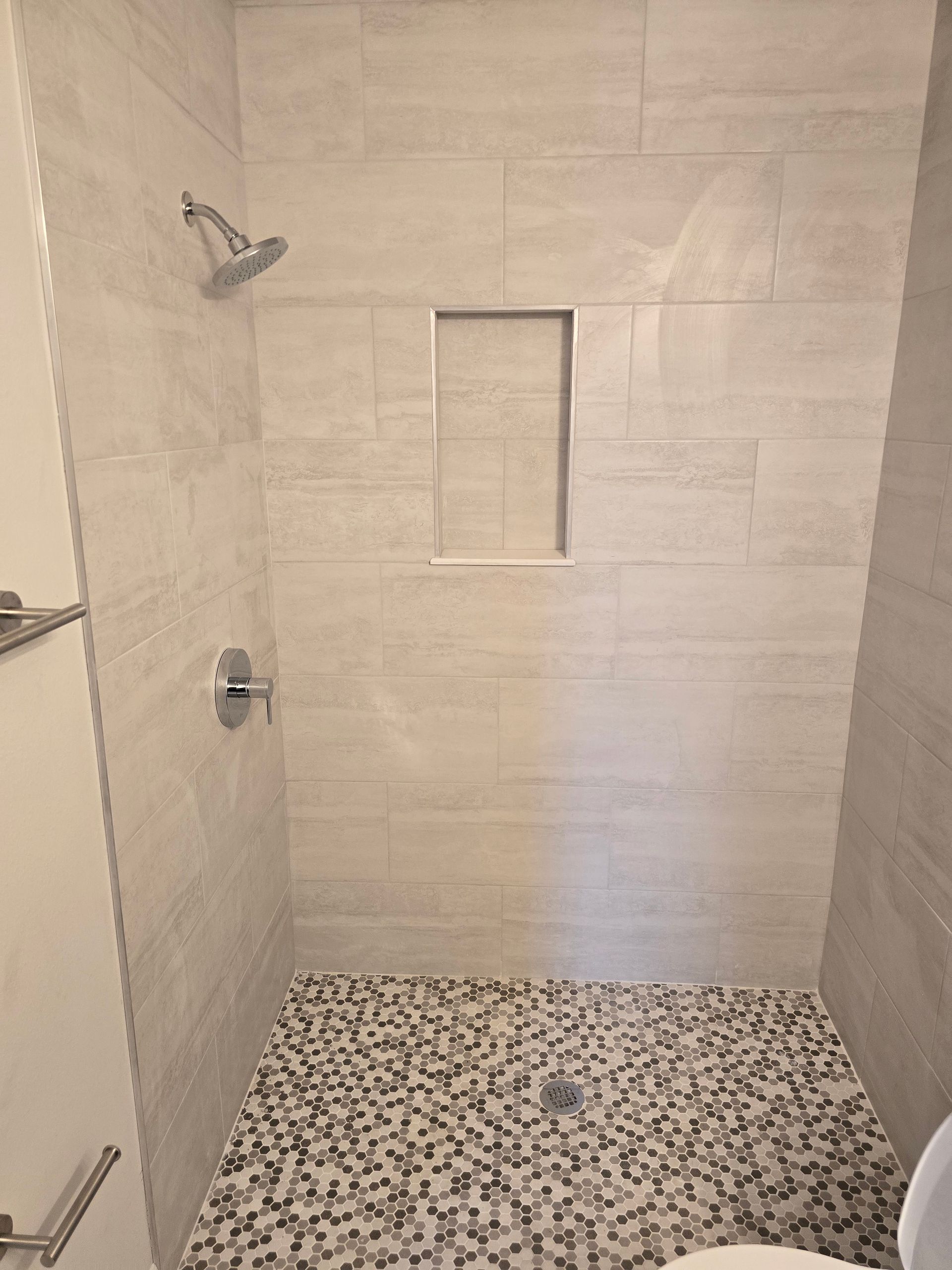 Bright marble bathroom with double vanity, large mirror, shower, and white cabinetry
