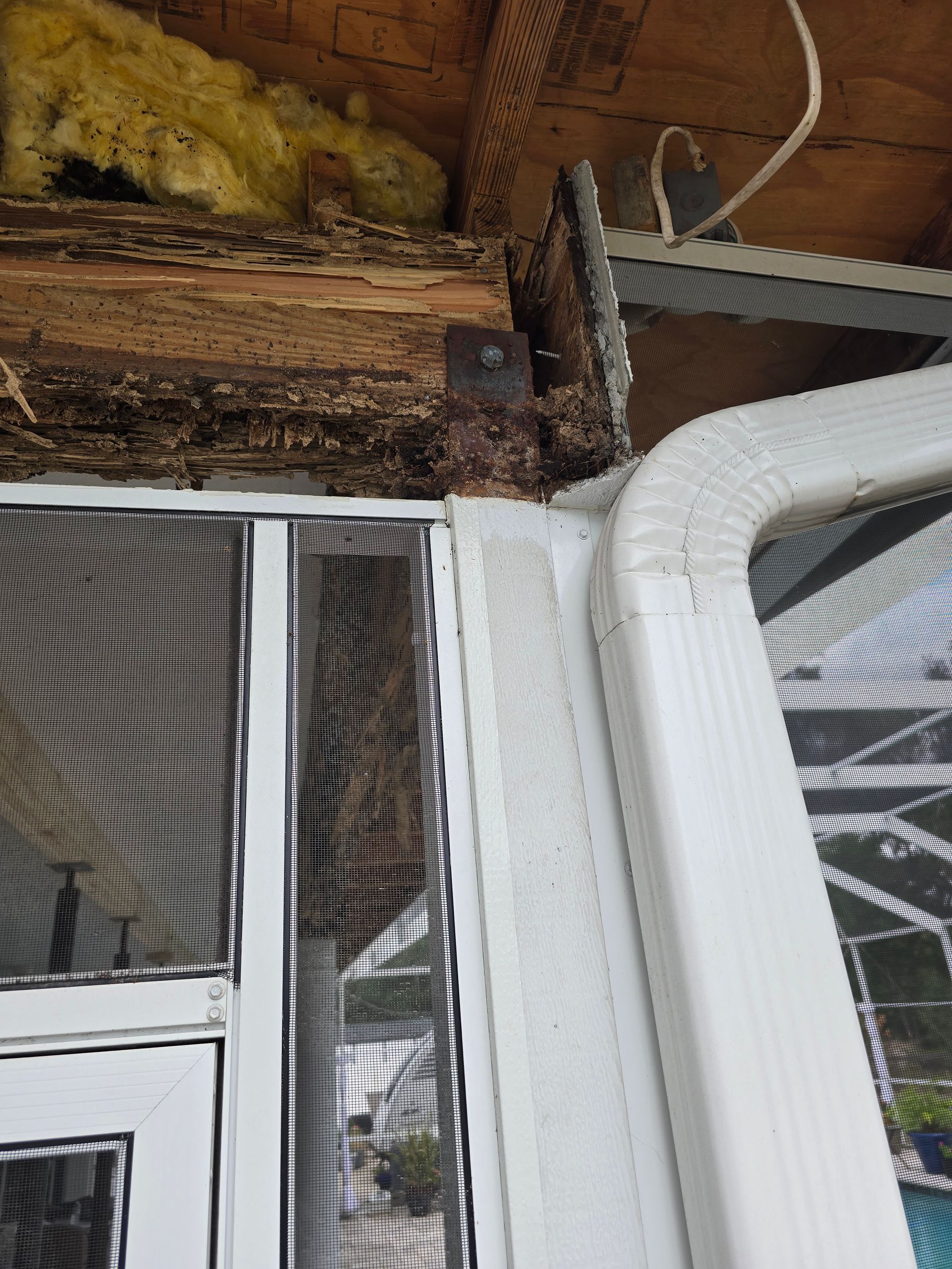 Damaged roof corner above a screened porch, with exposed wood, insulation, and white ducting