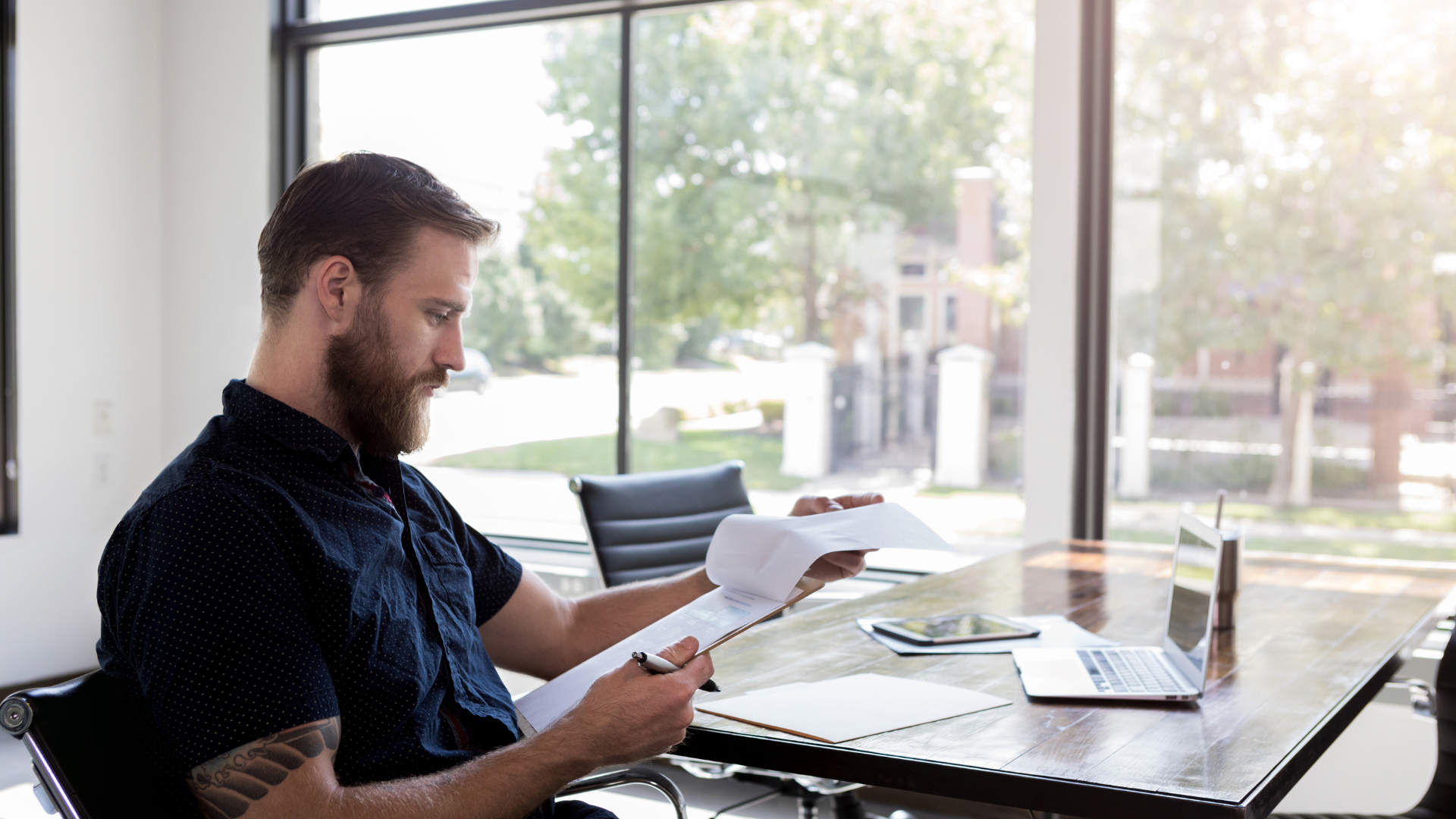 A man sitting in a chair reading a document