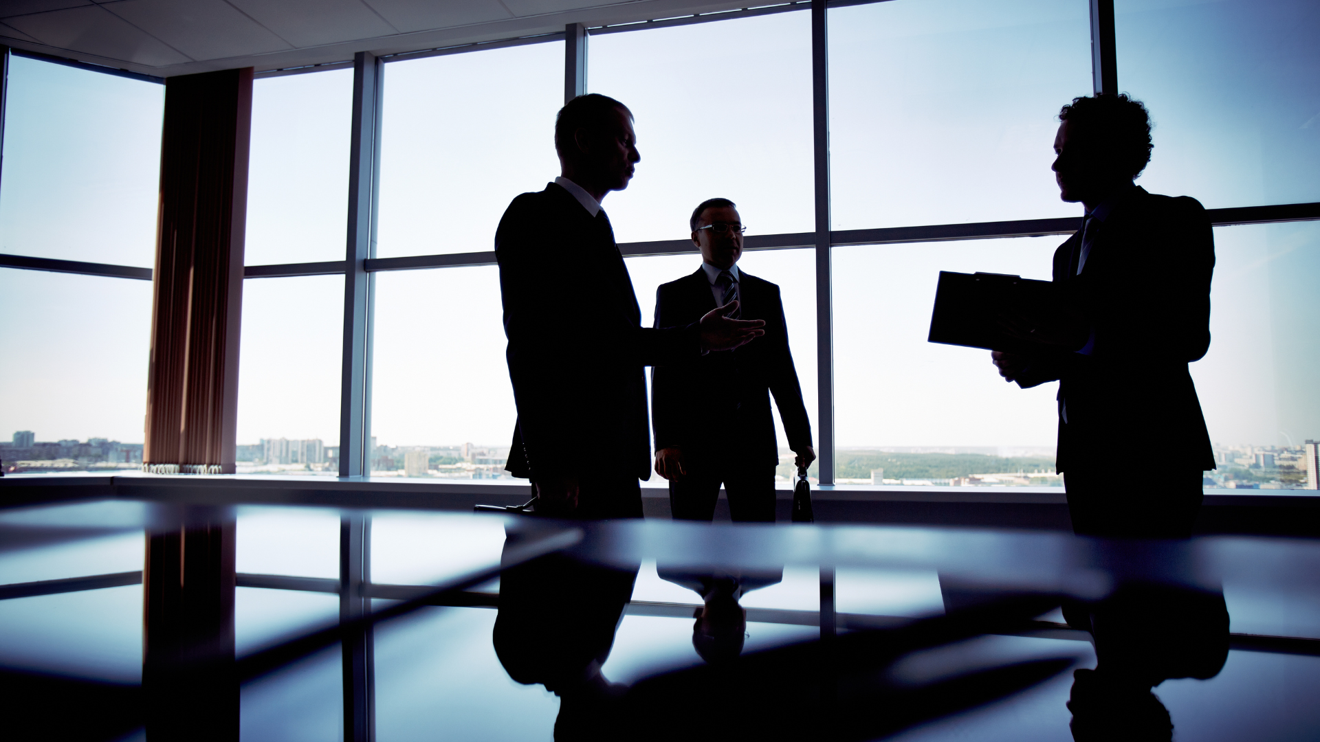 three men silhouette talking in an office