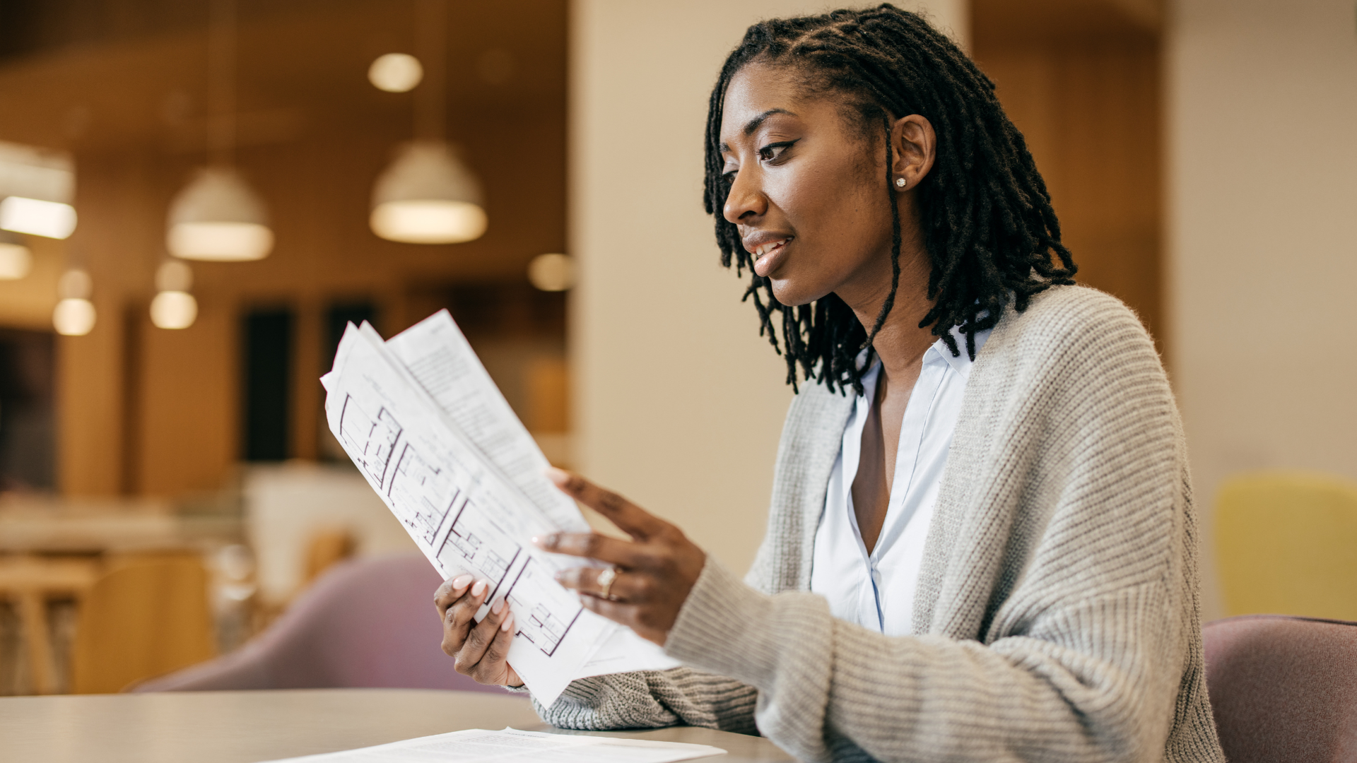 Businesswoman reviewing financial documents and floor plans while planning her next steps