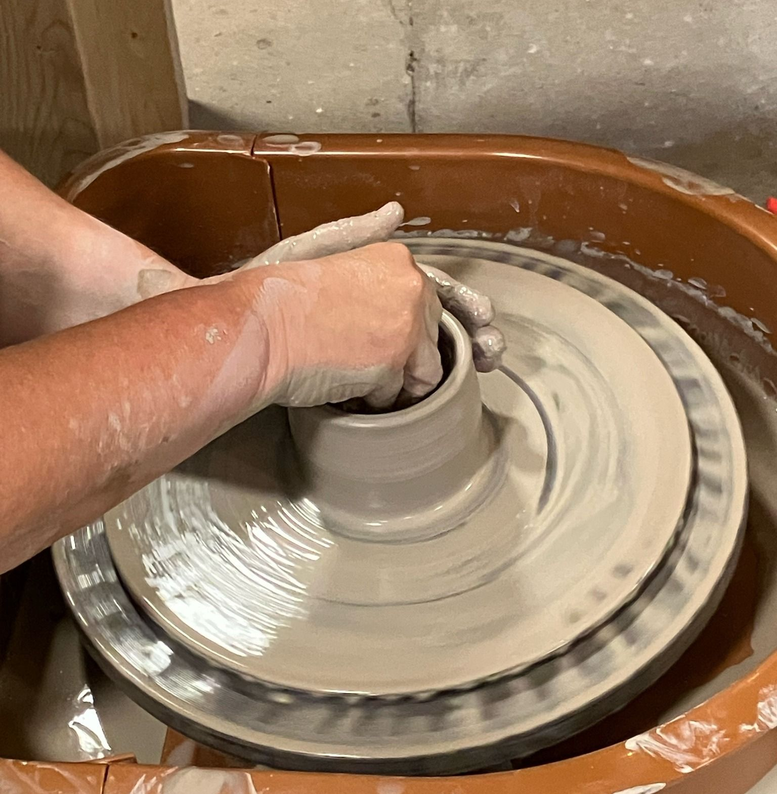 A person is making a pot on a pottery wheel