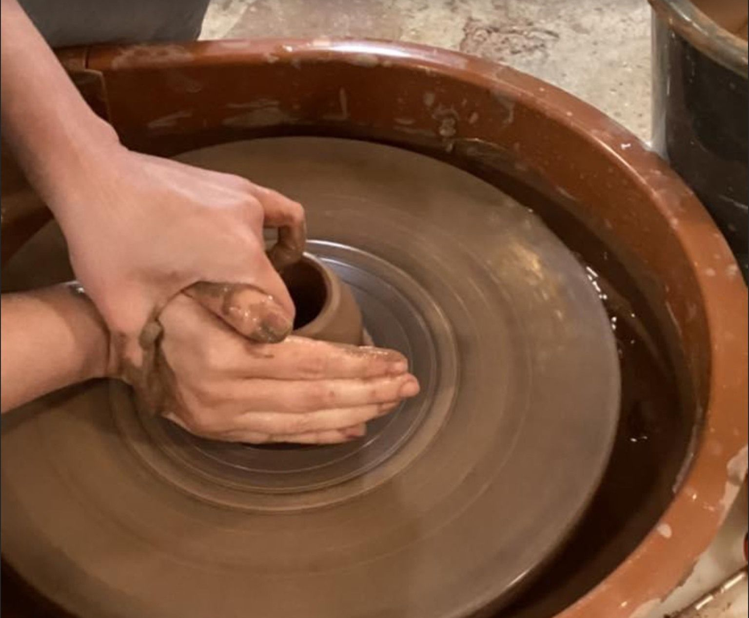 A person is making a pot on a pottery wheel