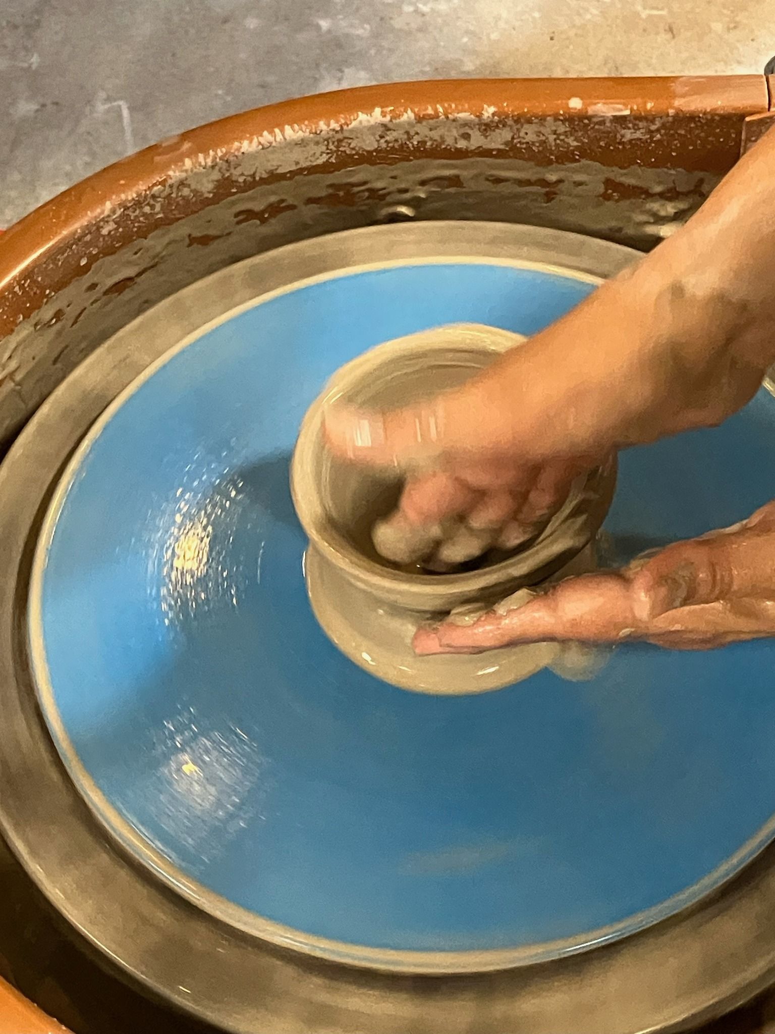 A person is making a pot on a pottery wheel