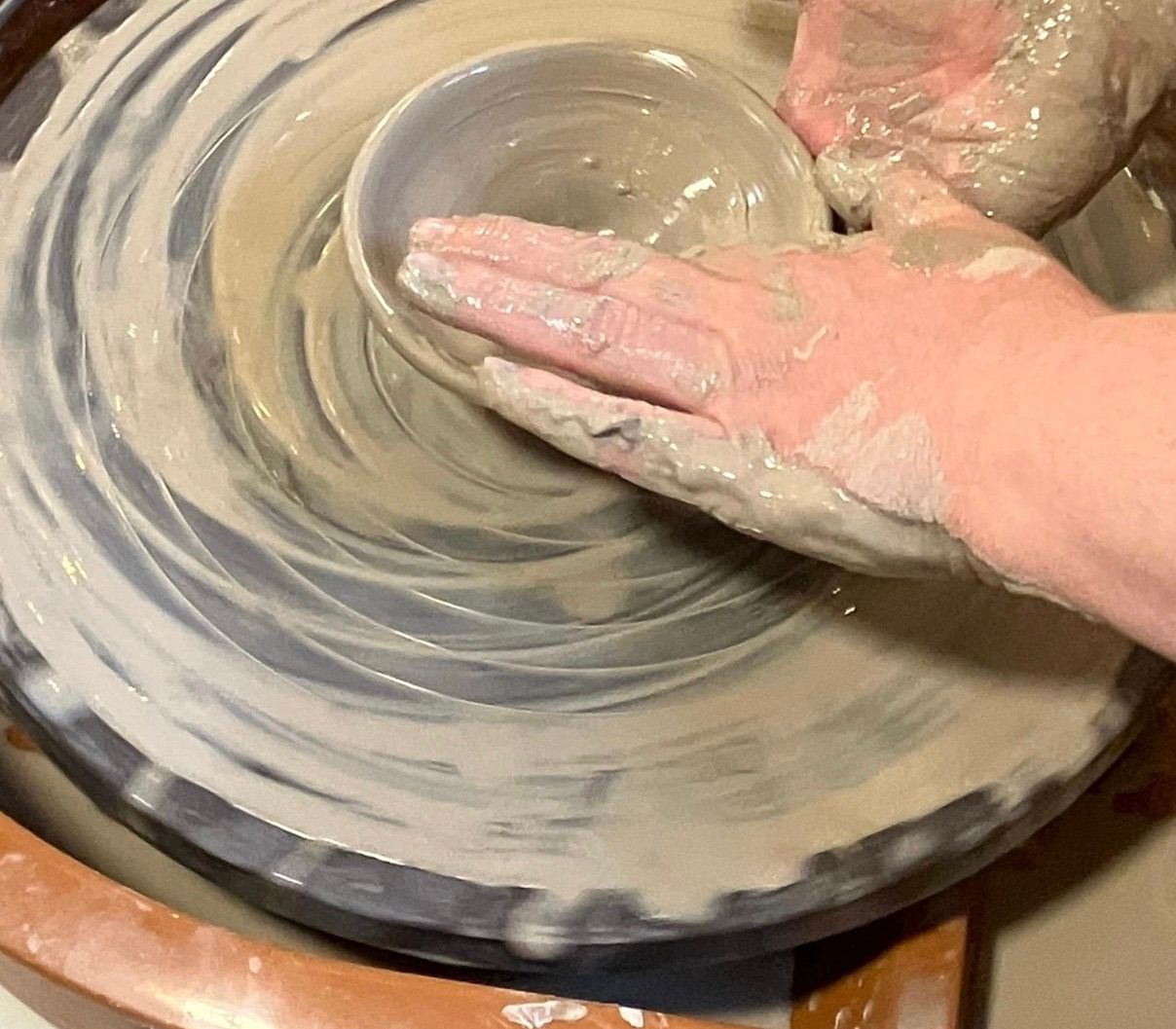 A person is making a pot on a pottery wheel