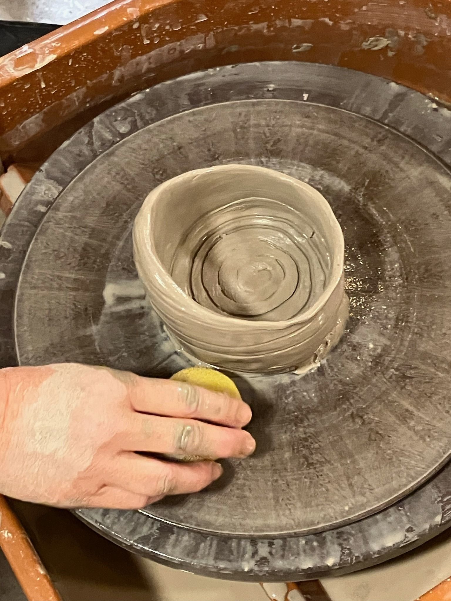 A person is making a pot on a pottery wheel