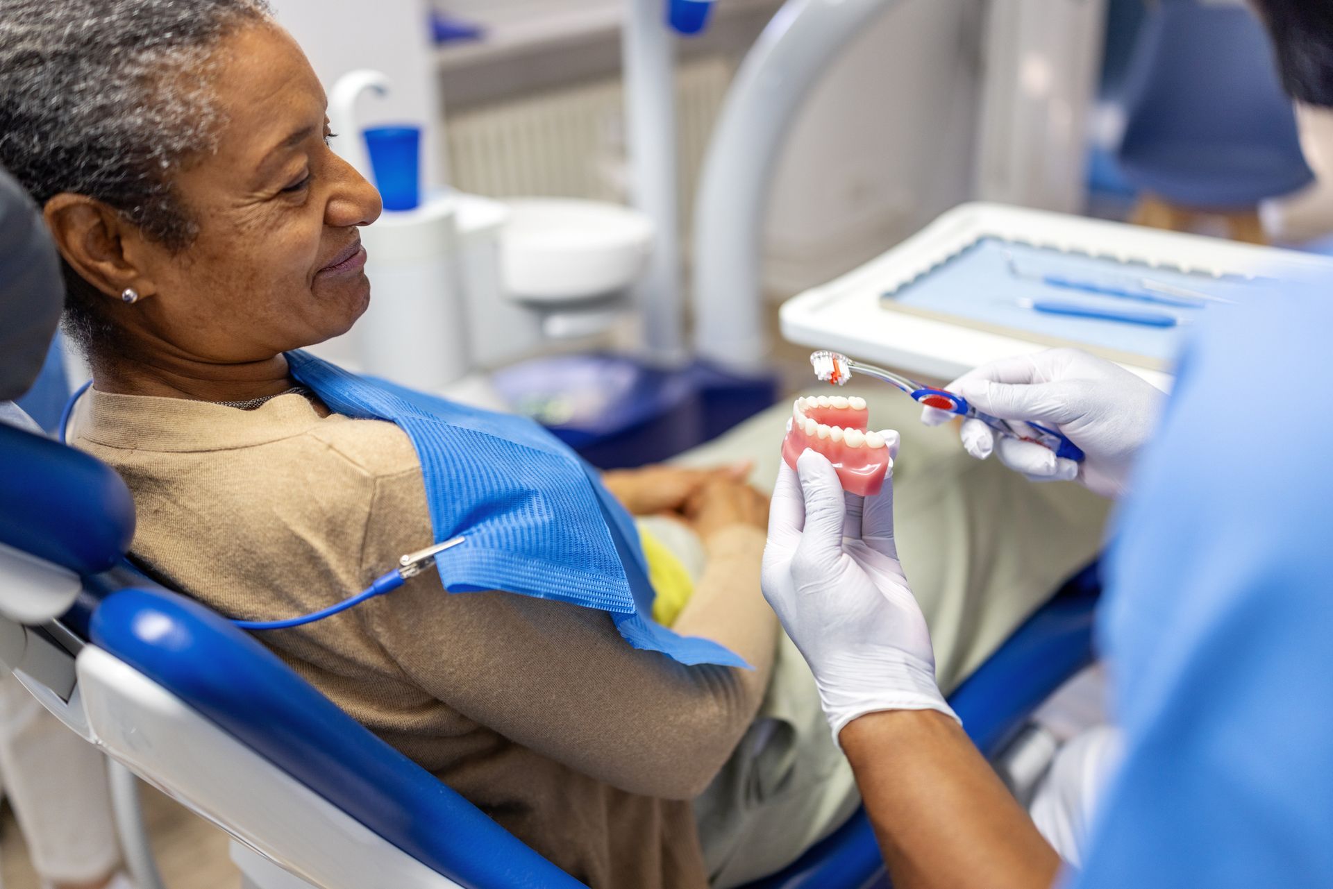 A dental patient watches a dentist clean dentures with a toothbrush in a dental office.