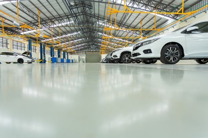 Modern car showroom with rows of white cars under bright industrial ceiling lights