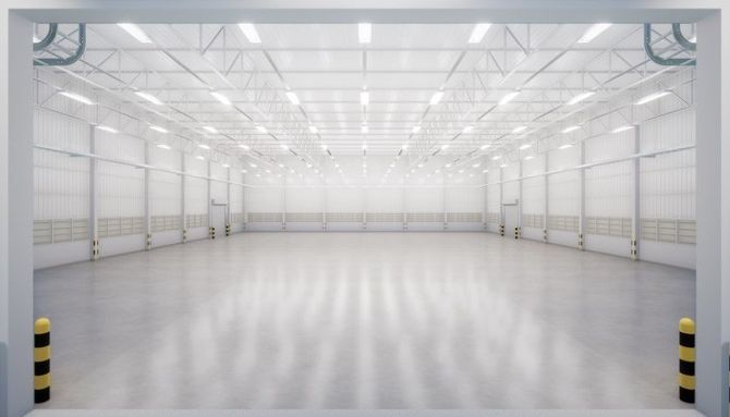 Empty white industrial warehouse interior with polished floor and overhead lights