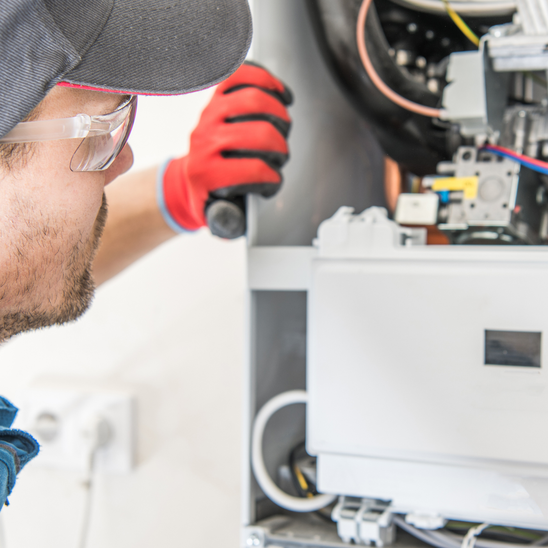 A person in safety glasses and gloves working on a machine.