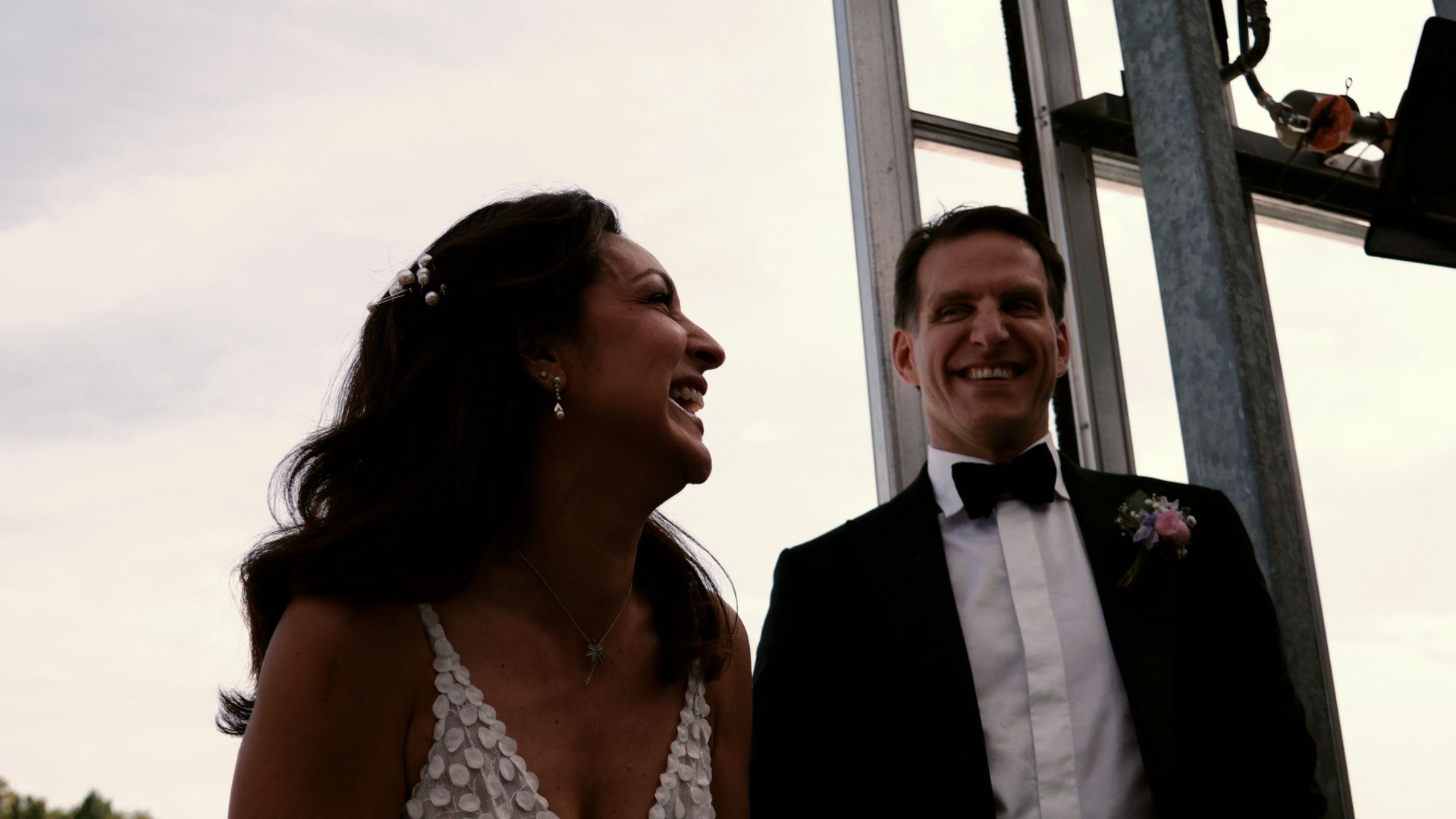 Smiling couple in formal wear on an outdoor amusement ride at sunset