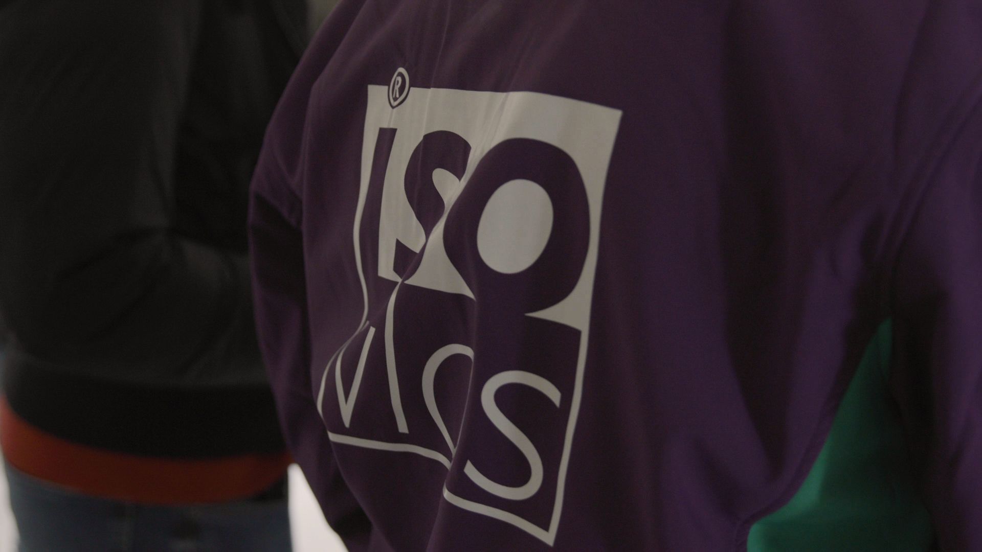 Purple shirt with a white “ISO” logo on the chest in a dim indoor setting