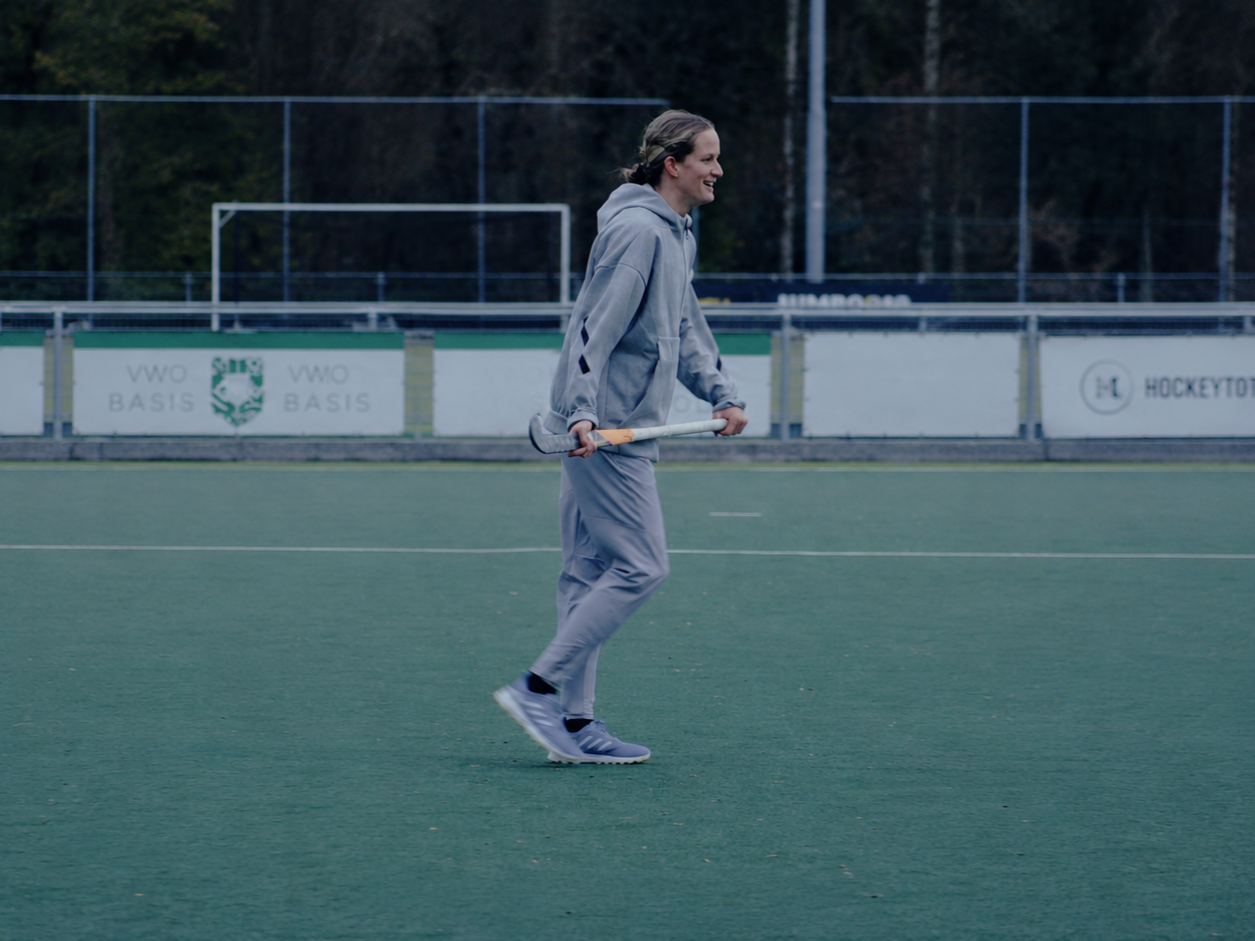 Person in gray sportswear holding a tennis racket on an outdoor court