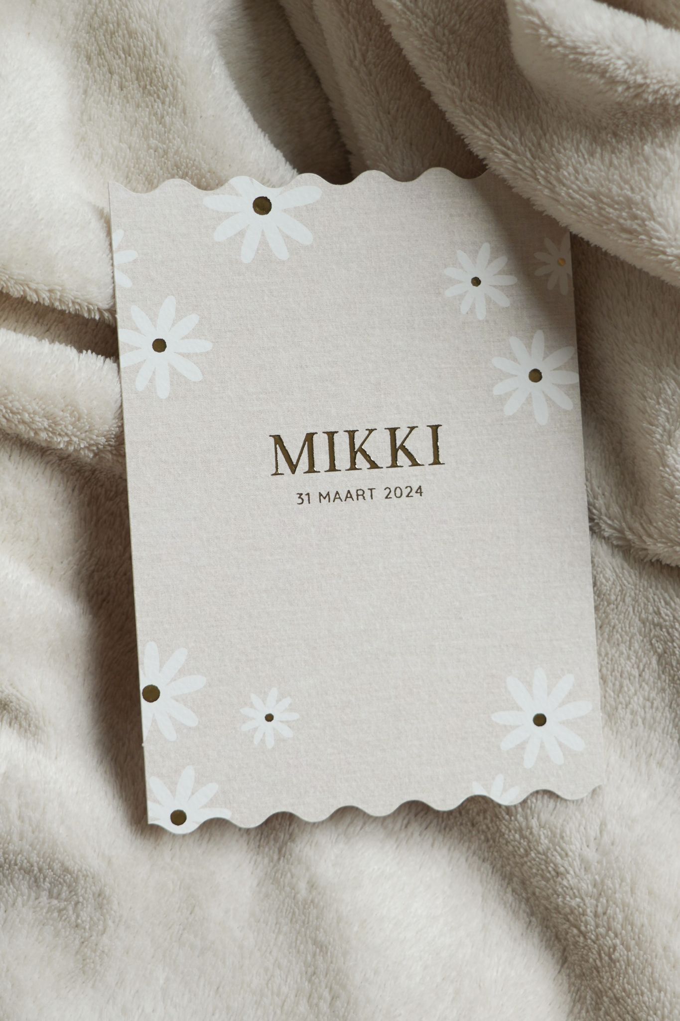 White scalloped card with “MIKKI” logo on soft beige fabric background