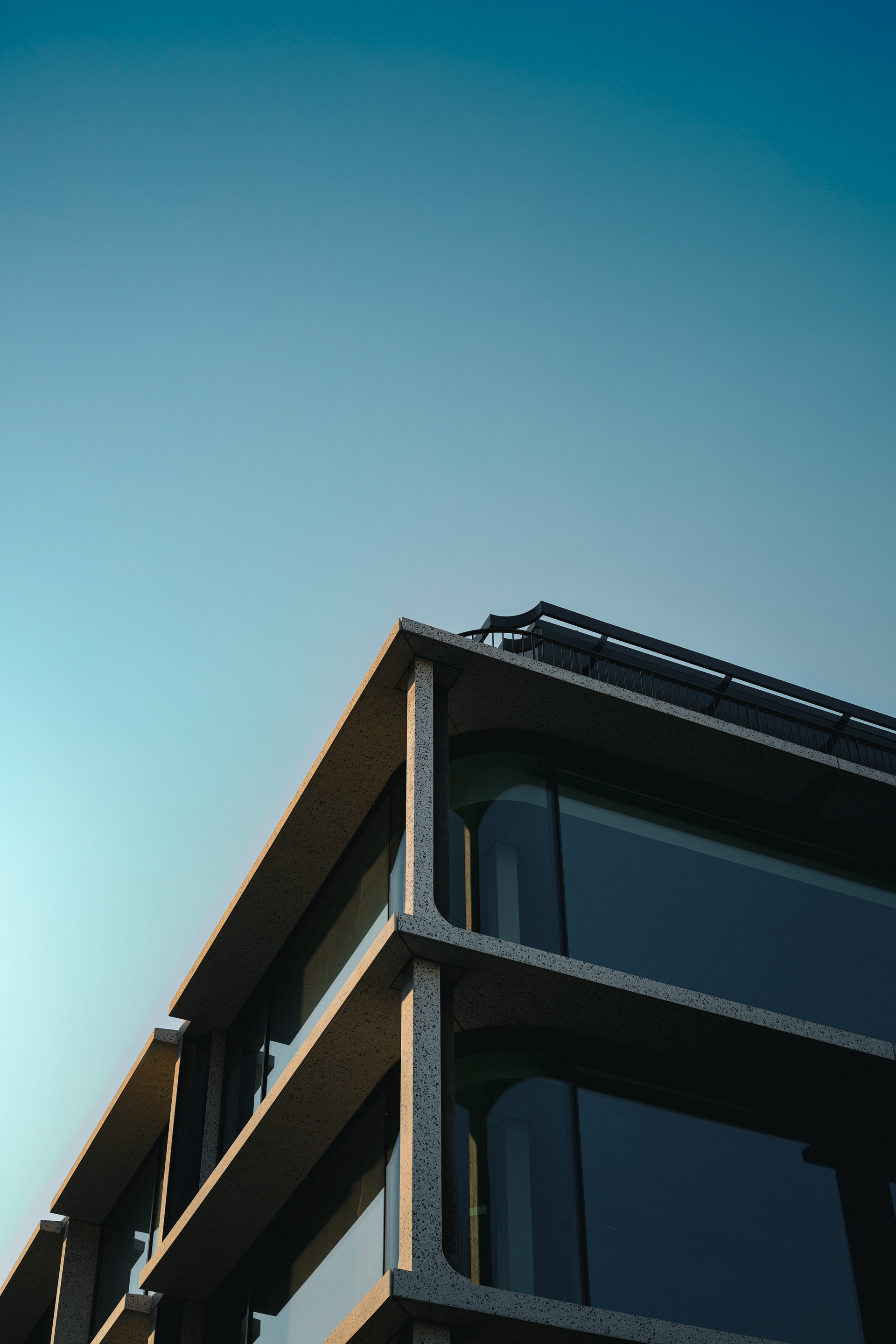 Modern building corner with dark glass balconies against a blue sky