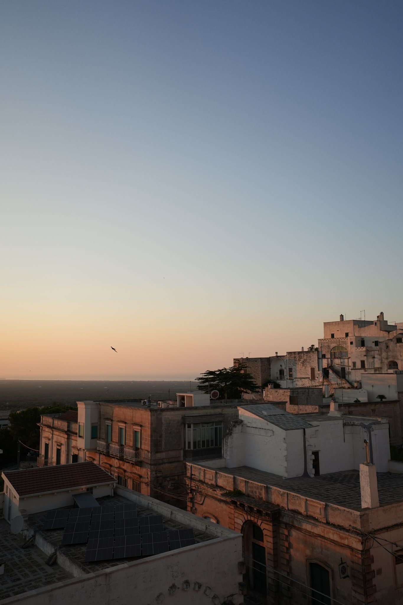 Sunset over a coastal town with white buildings and a pastel sky