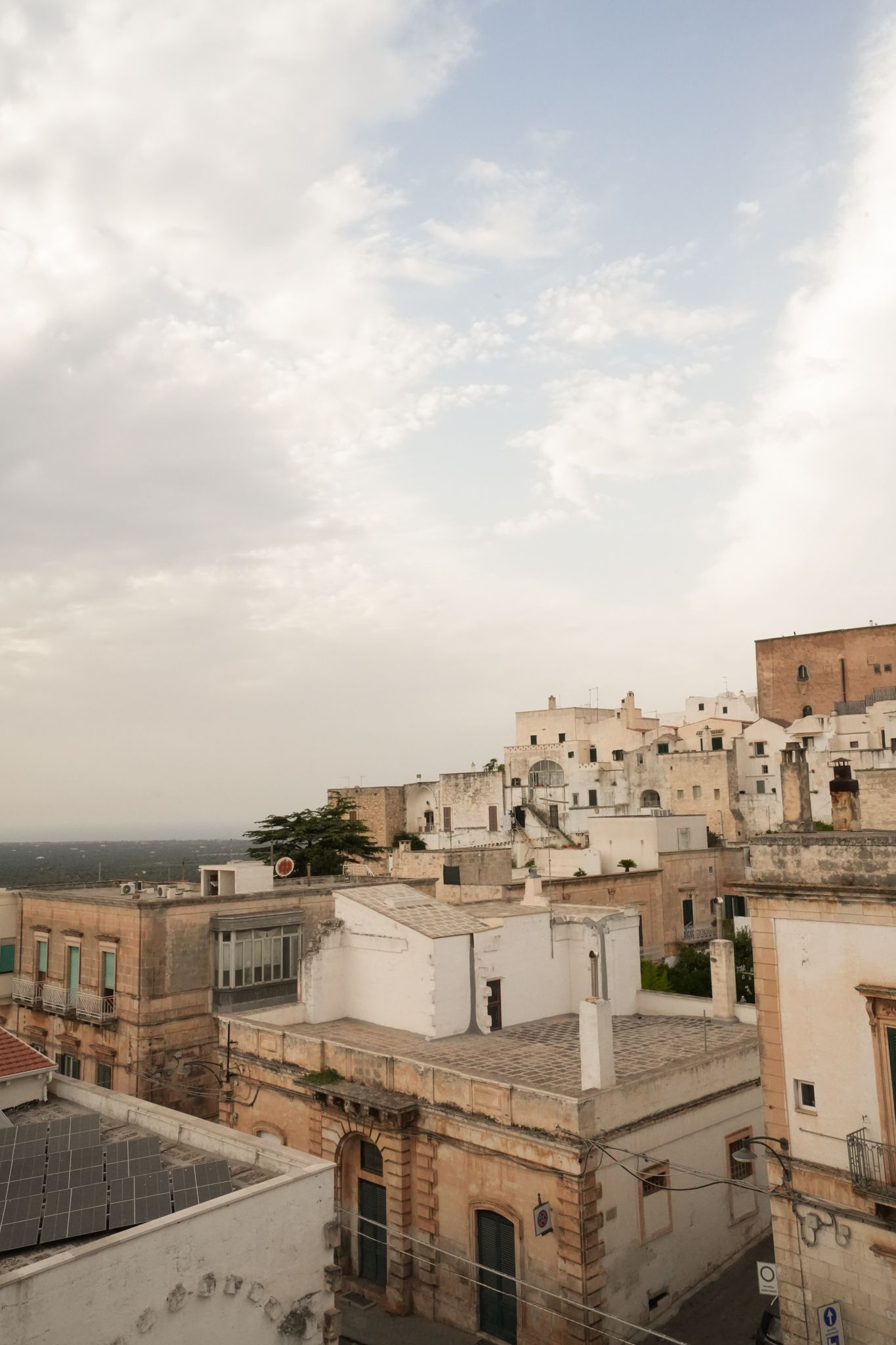 Hilltop town with white and tan buildings under a cloudy sky at dusk
