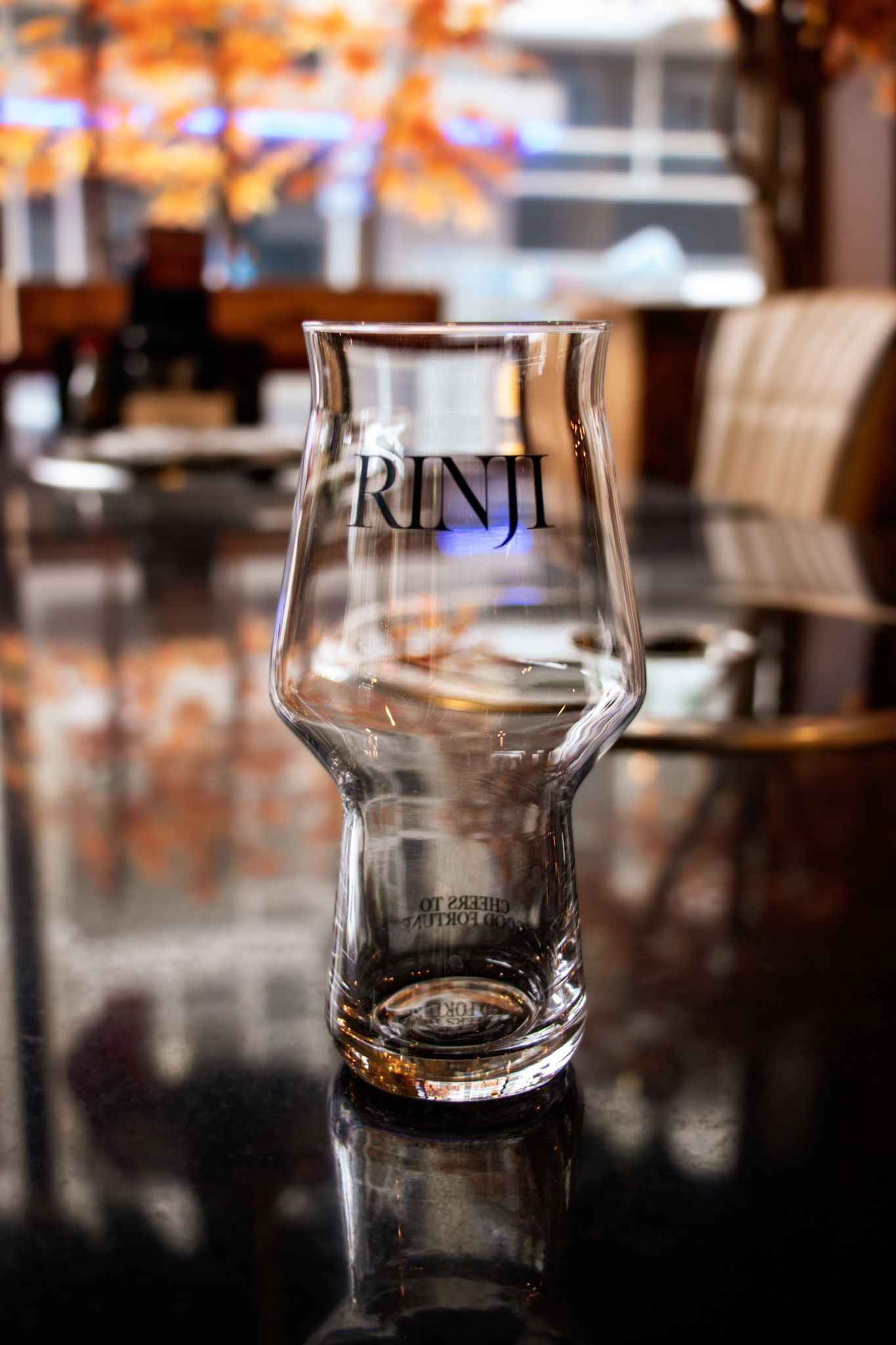 Empty branded glass on a reflective café table with a blurred restaurant interior in the background