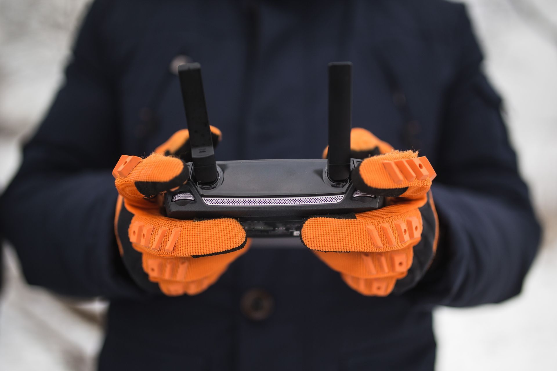 Drone pilot training A person wearing orange gloves is holding a remote control in their hands.