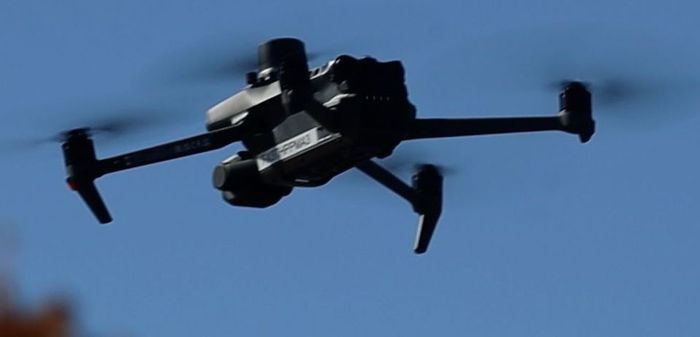 A drone is flying through a blue sky.