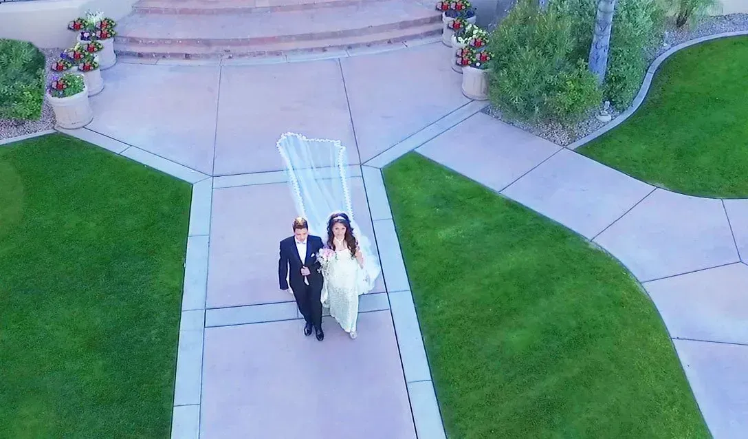 Photo by Phoenix Drone Pros, Robert Biggs, An aerial view of a bride and groom walking down a sidewalk.