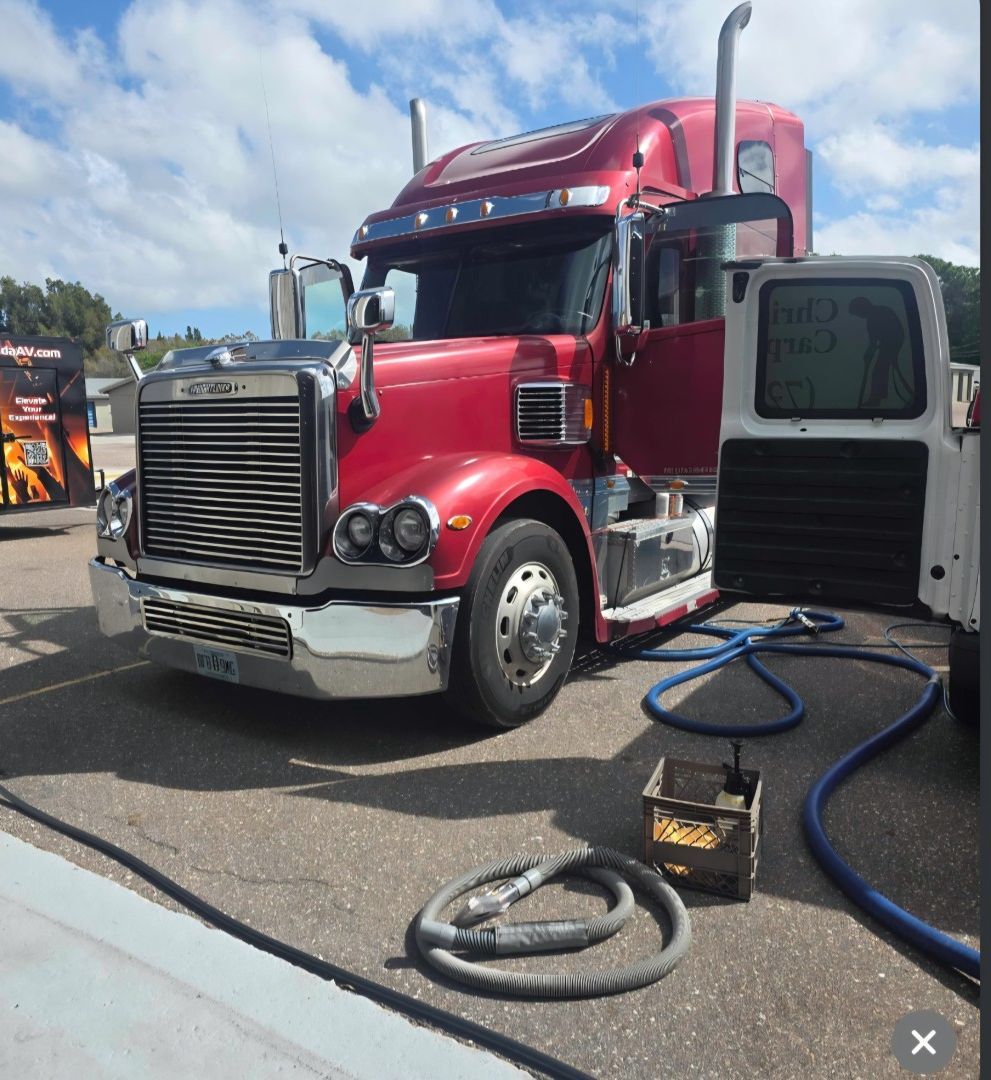 Van-mounted extractor hoses and a handheld upholstery tool at a semi truck during carpet cleaning in Largo, FL